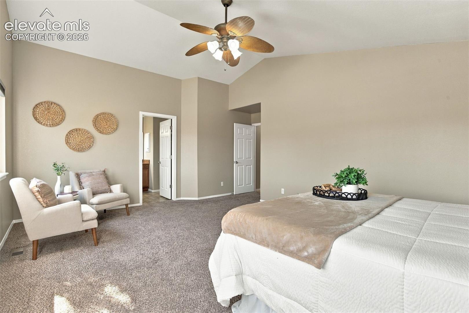 Vaulted ceiling with a ceiling fan, neutral wall tones, and carpet flooring