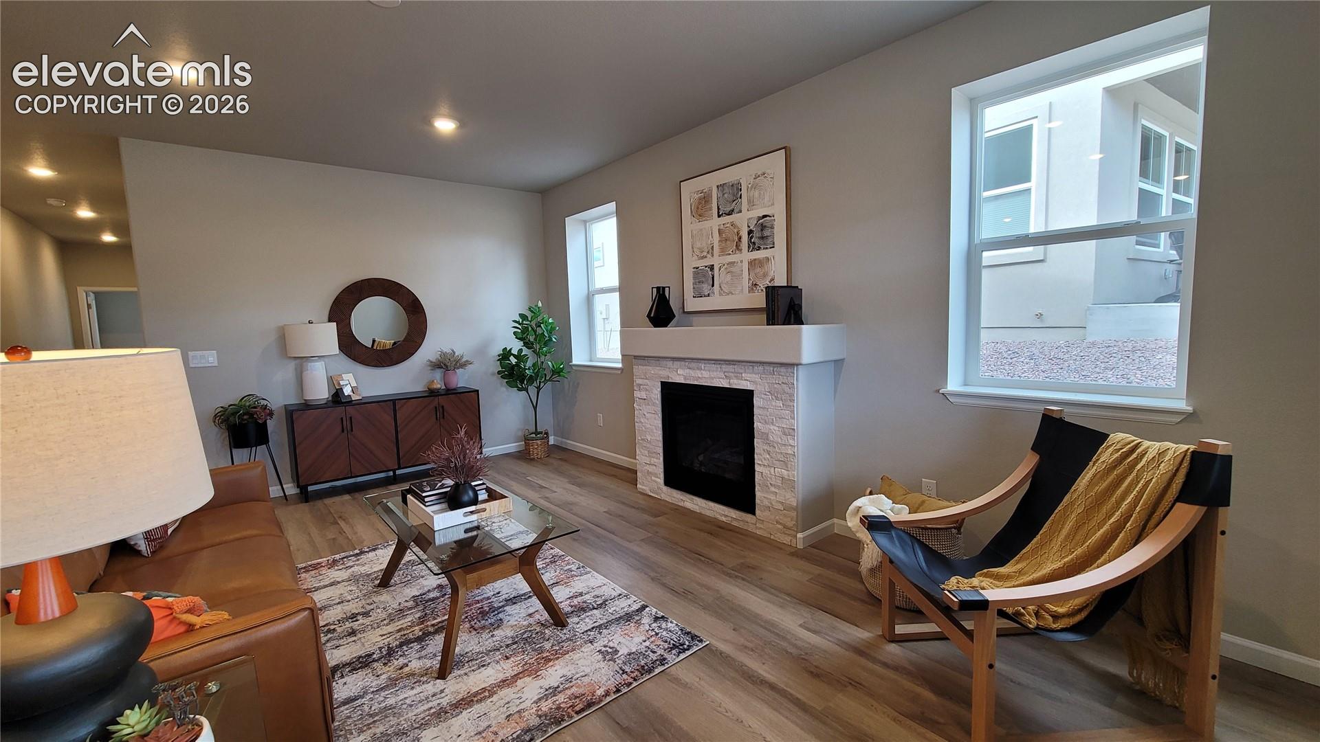 Living space featuring LVP flooring, recessed lighting, and a fireplace with a stone surround and drywall mantle