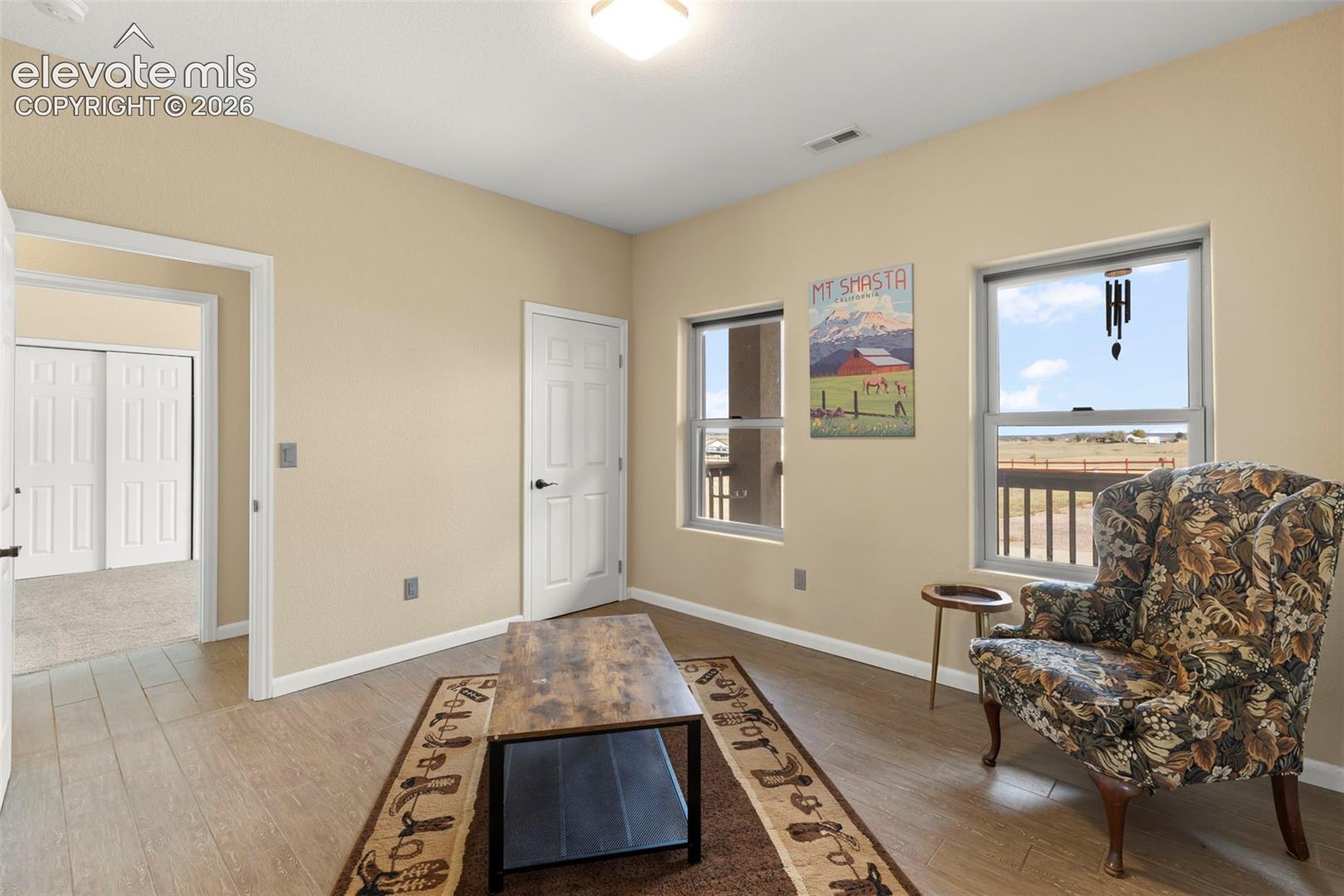 Interior space featuring neutral wall paint, wood-finish flooring, two large windows, and a six-panel door
