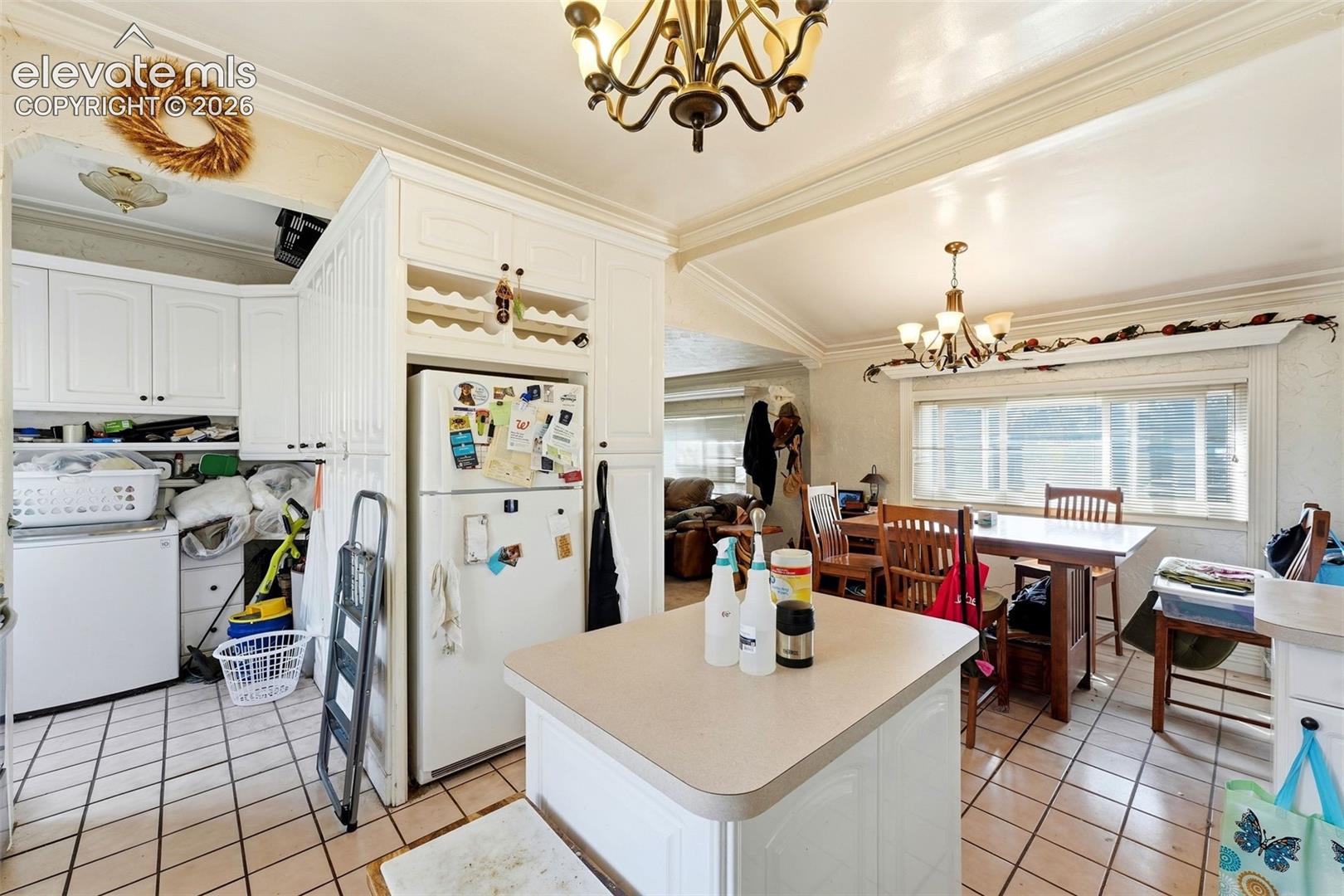 White cabinetry with built-in wine rack, centered kitchen island, and tile flooring