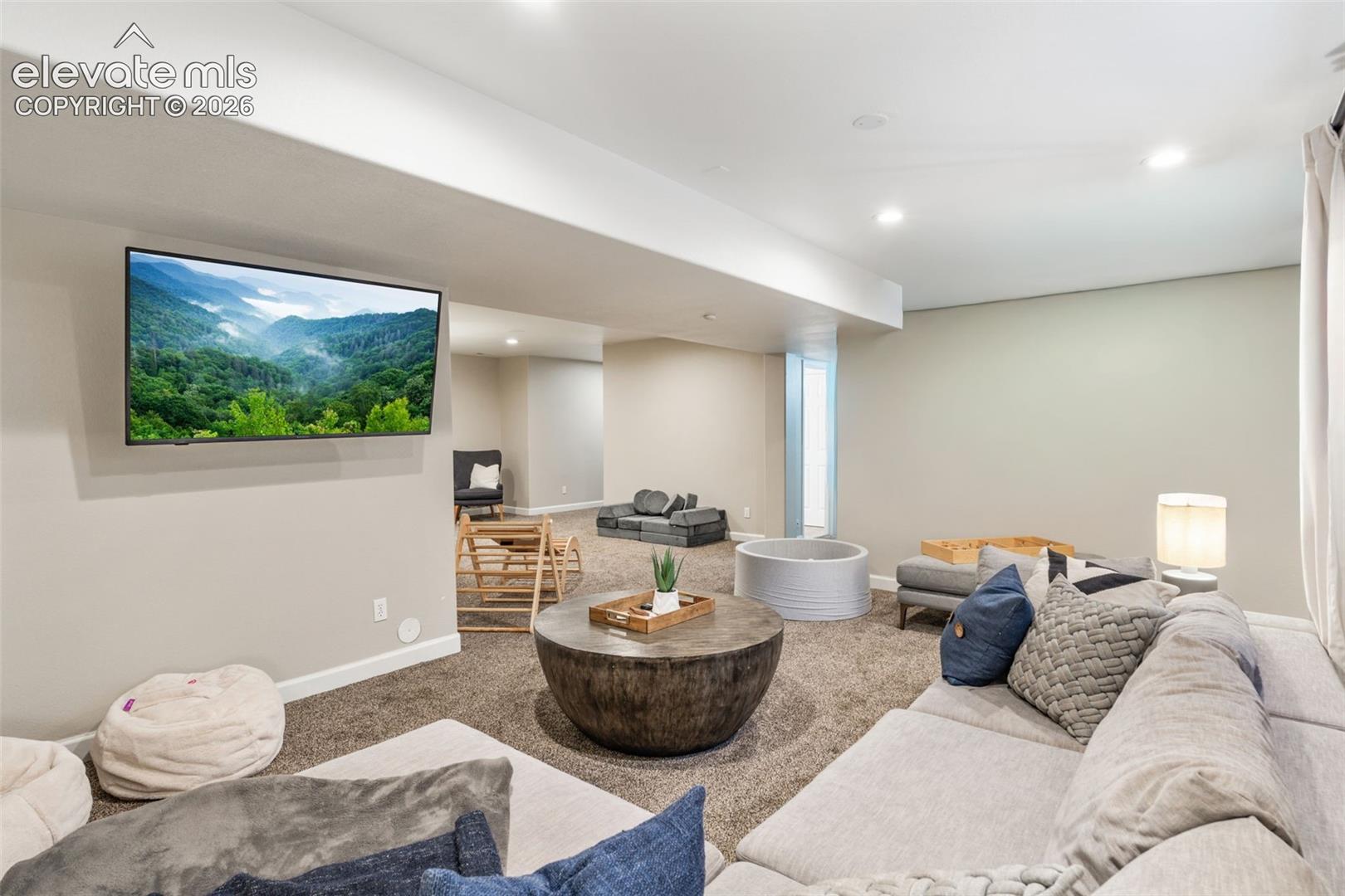 Neutral-toned interior space featuring recessed ceiling lighting, wall-to-wall carpeting, and a wall-mounted television