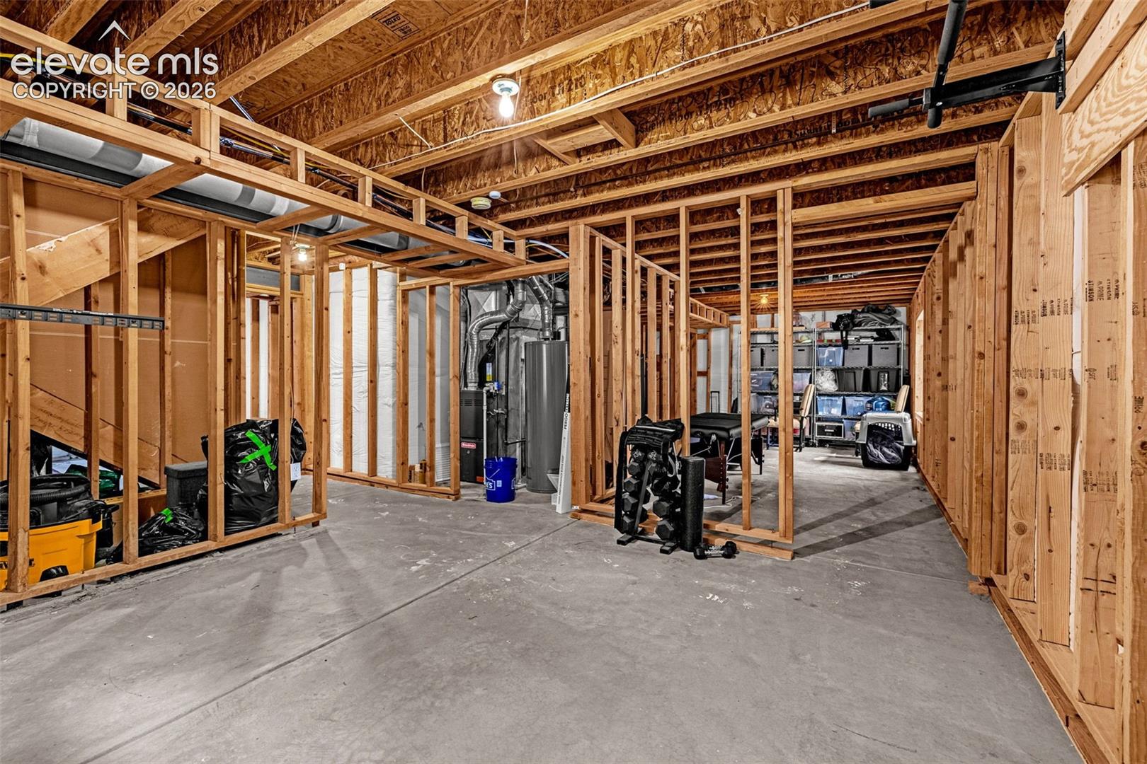 Unfinished basement area featuring exposed timber framing, concrete flooring, and mechanical systems