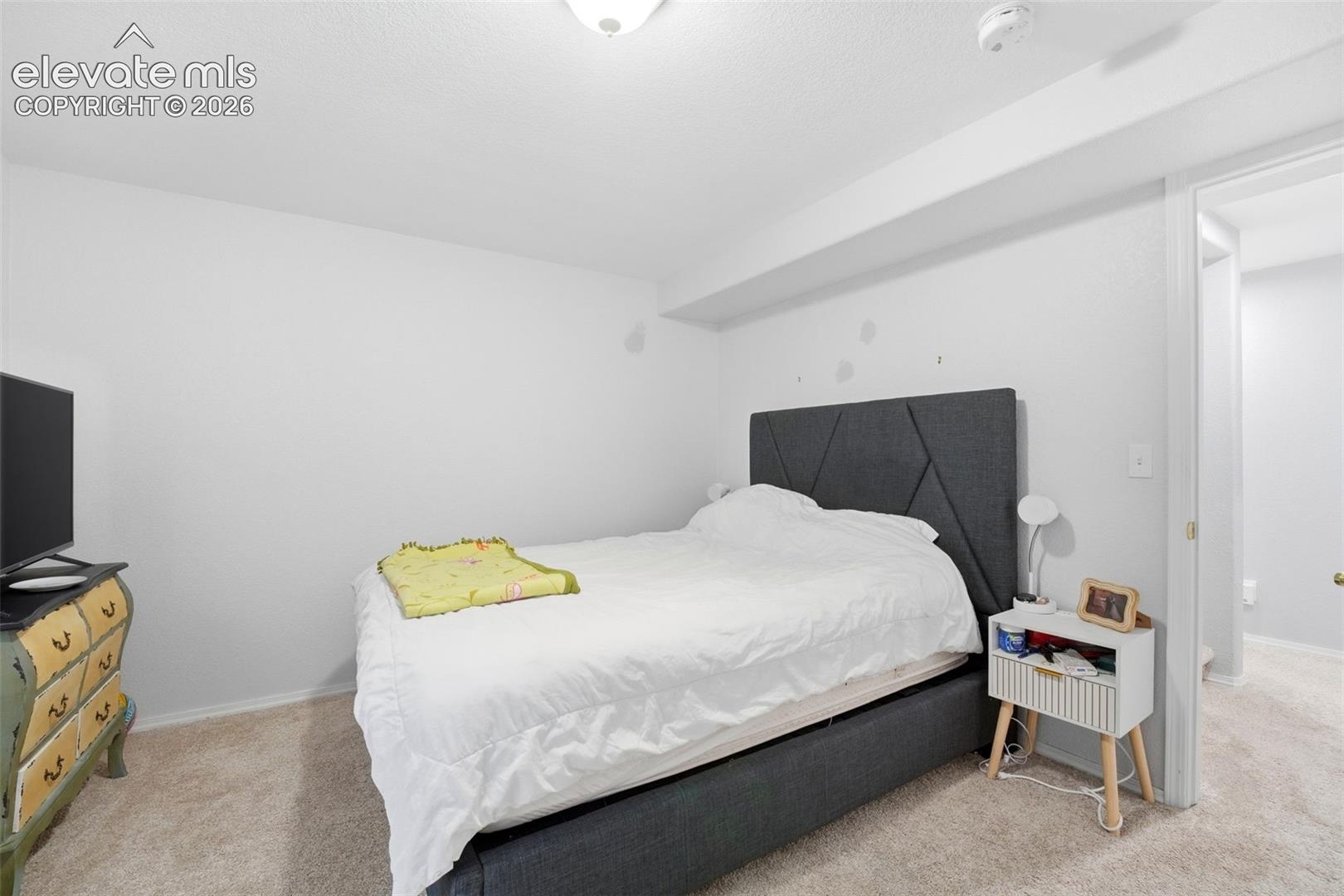 Carpeted room featuring a geometric upholstered headboard, recessed lighting, and a white ceiling