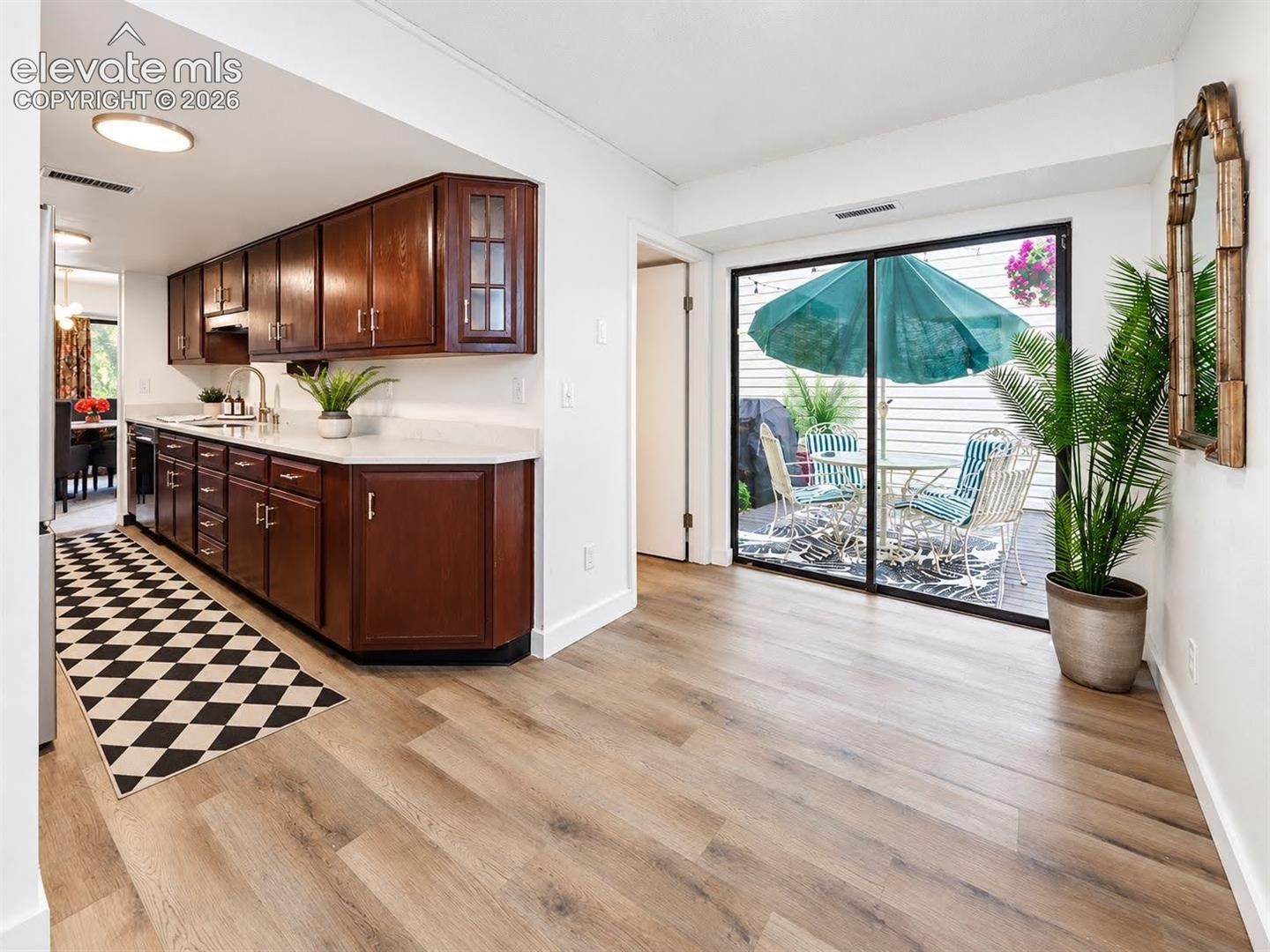 Kitchen featuring stained wood cabinetry, white countertops, wood-finish flooring, and sliding glass doors
