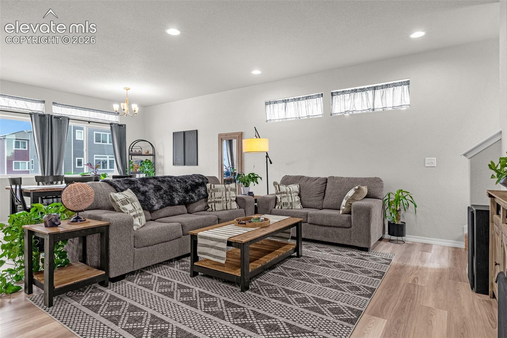 Open-concept living area with light wood-finish flooring, recessed lighting, and white walls