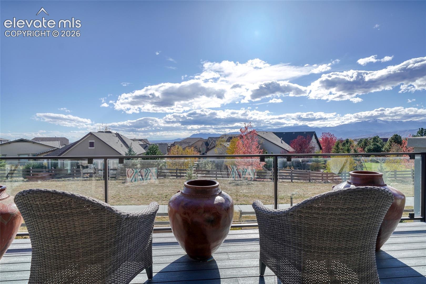 Elevated deck featuring composite flooring, glass panel railings, and mountain backdrop