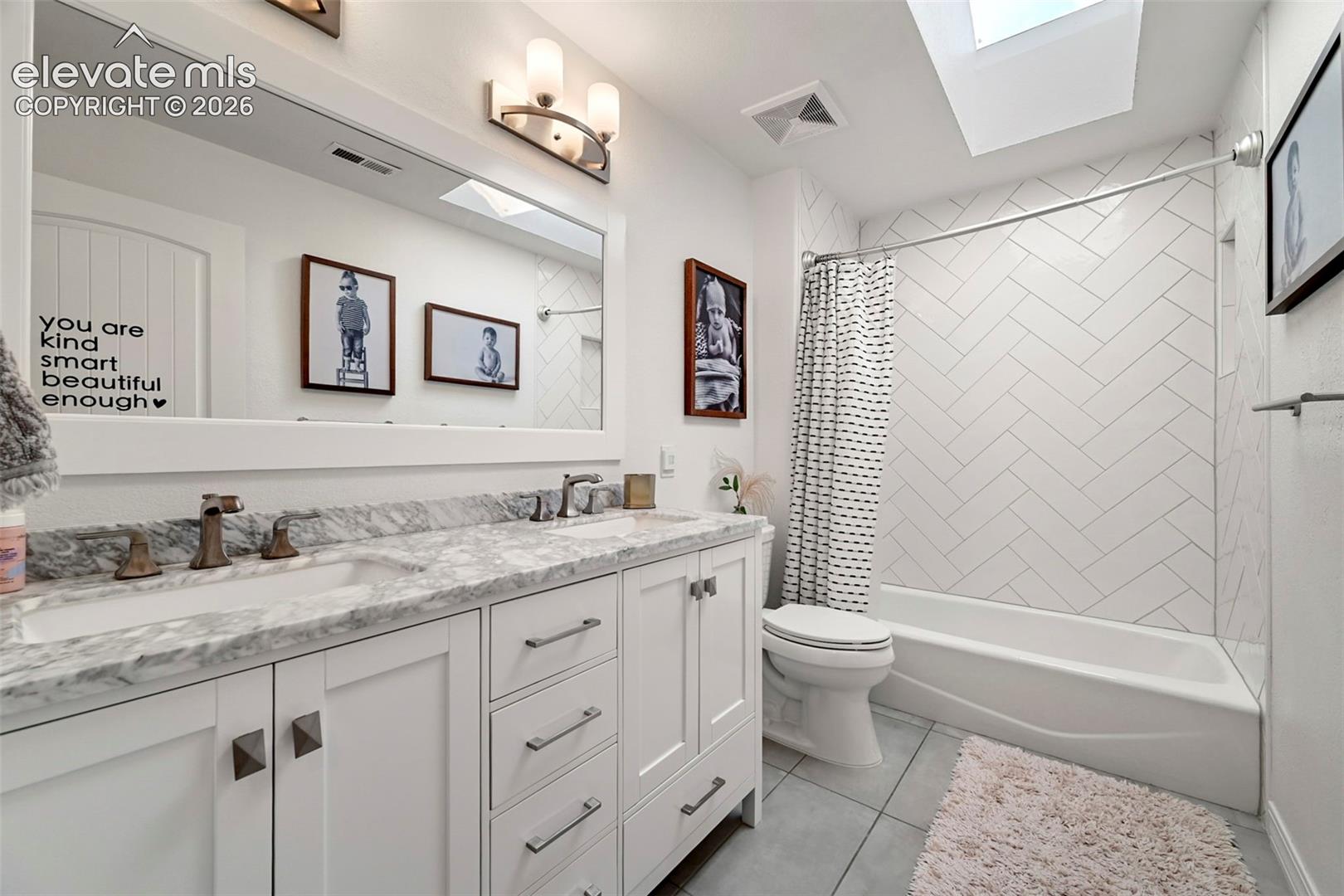Dual vanity with a stone countertop, undersink cabinetry, and integrated sinks