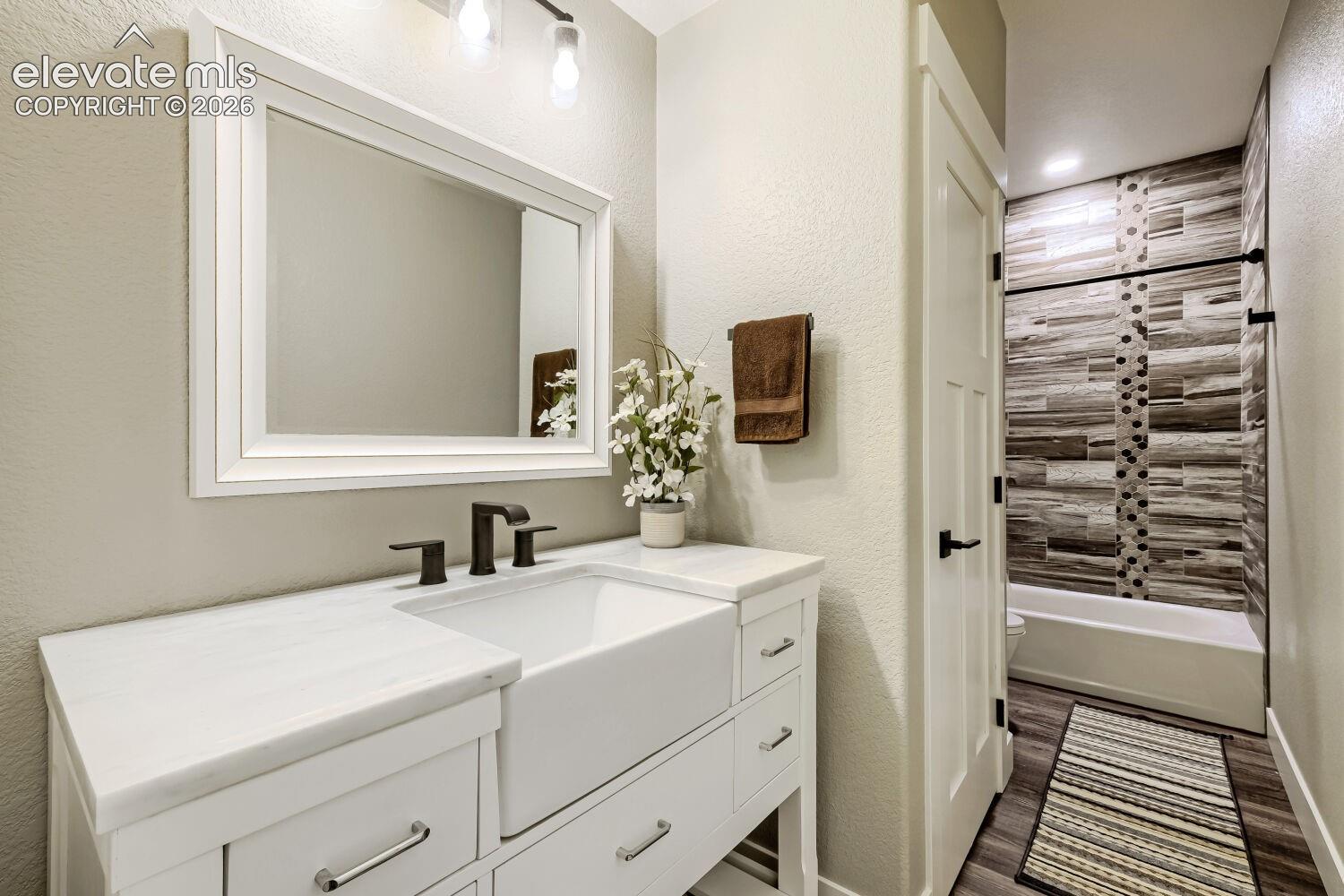White vanity with an integrated farmhouse sink, dark bronze-finish faucet, and a framed mirror