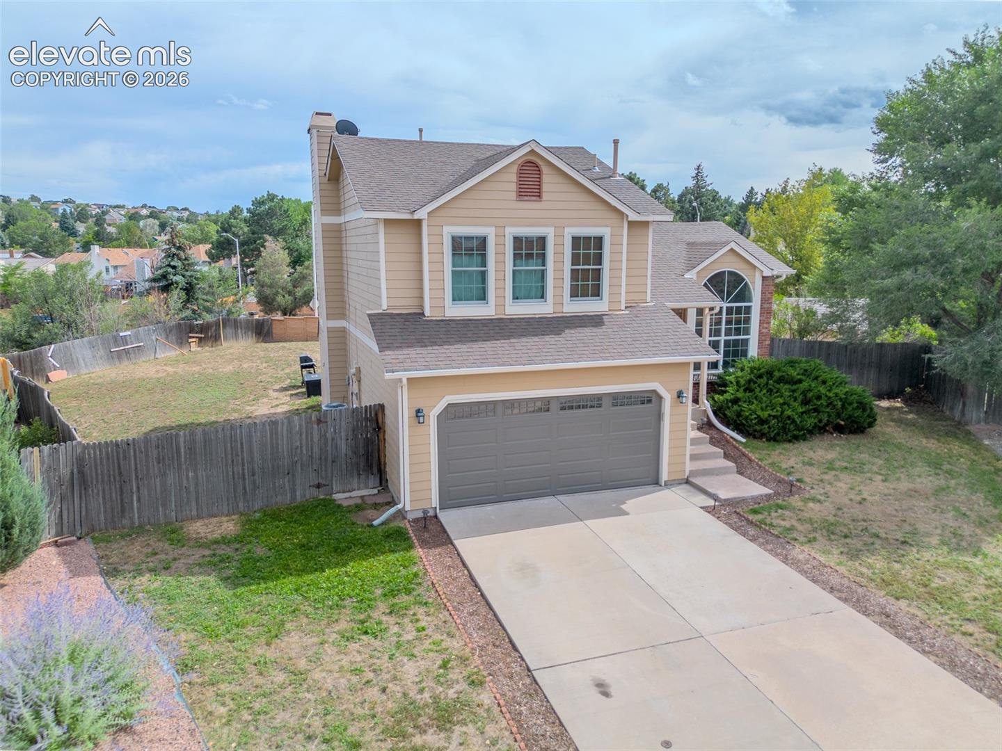 Two-story residence with a two-car garage, multiple windows, and a fenced backyard