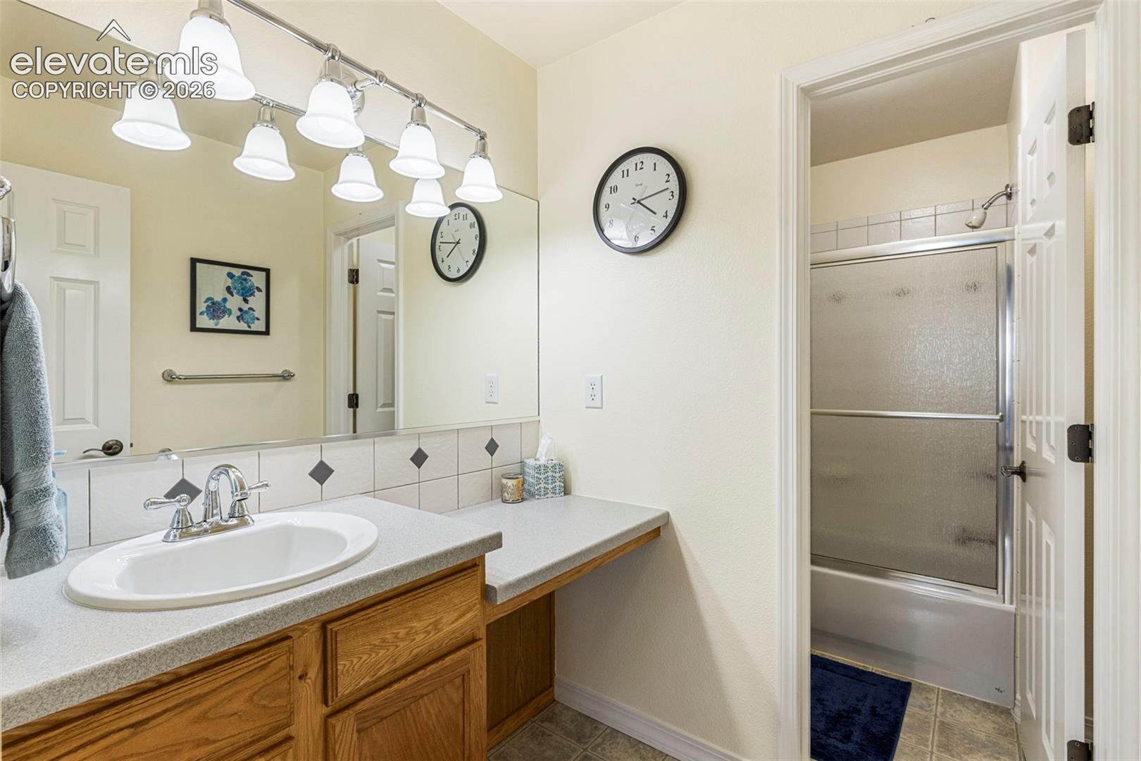 Bathroom featuring a vanity with wood-finish cabinetry, a single basin sink, and a laminate countertop