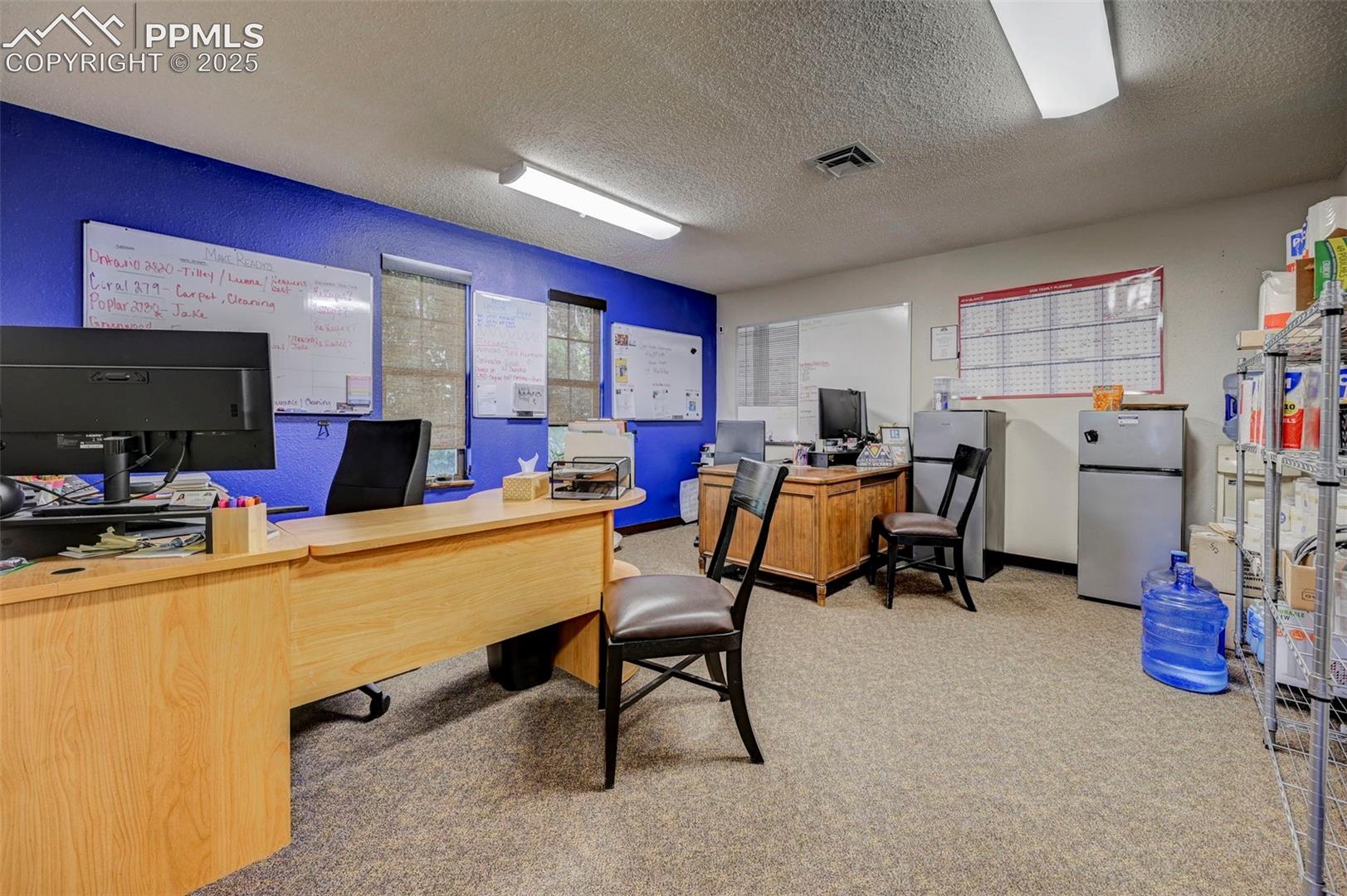Office area featuring carpet floors and a textured ceiling
