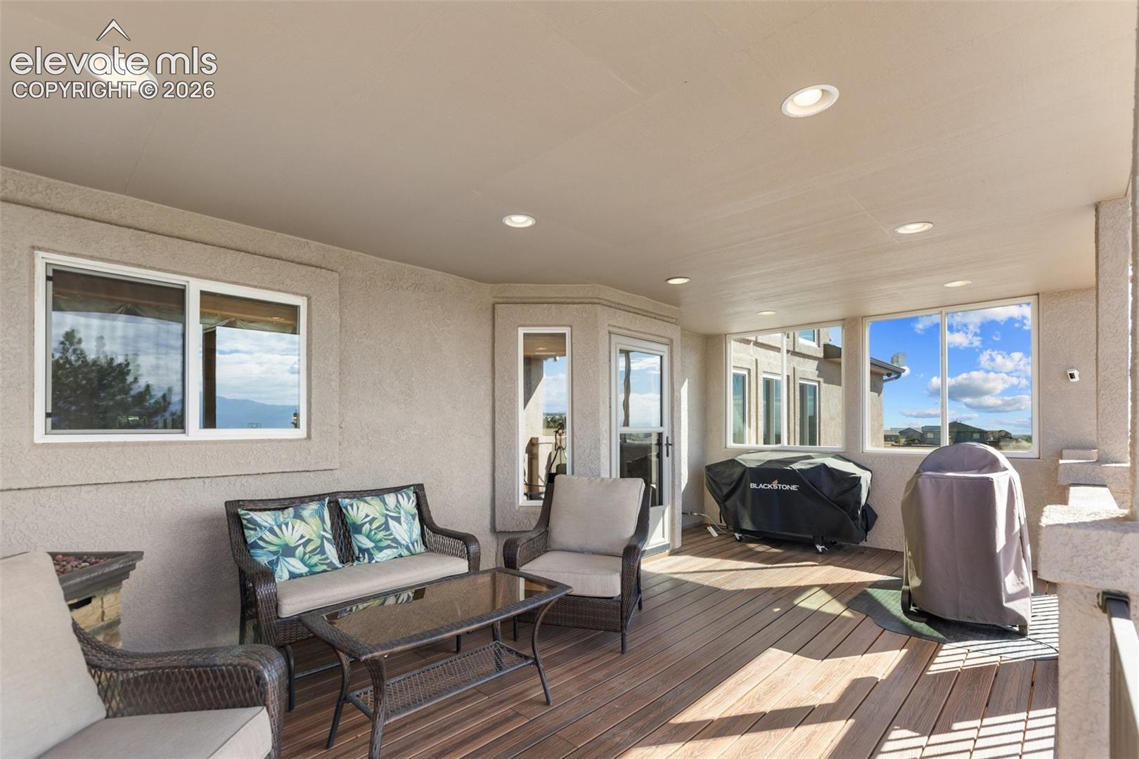 Covered patio featuring wood-finish decking, recessed ceiling lighting, textured wall finish, and multiple window placements