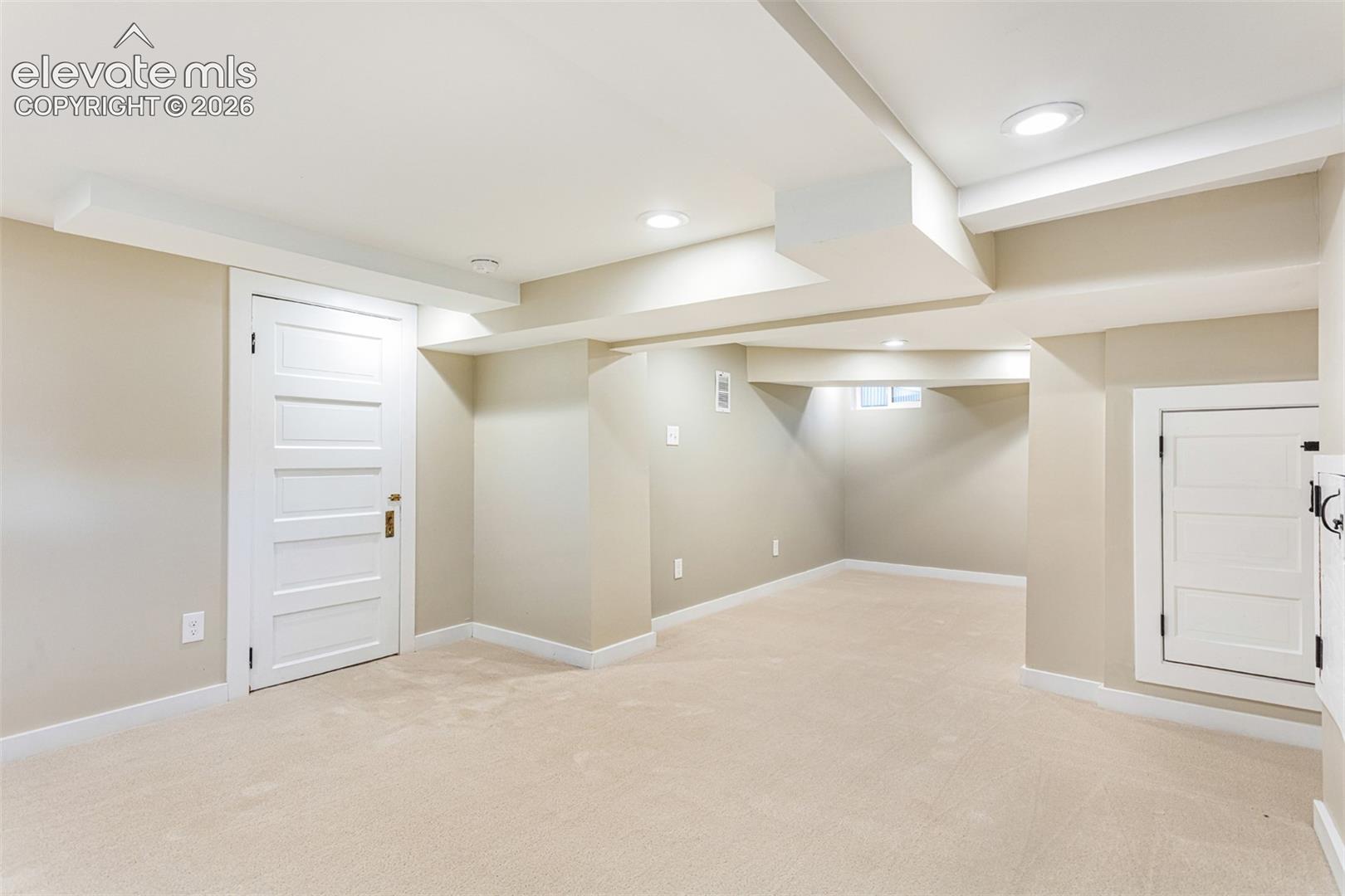 Spacious room featuring neutral carpeting, light-toned walls, and white trim