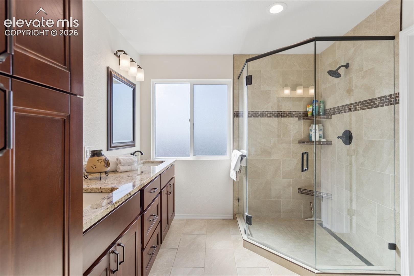 Updated primary bathroom with beautiful cabinetry, solid surface-double sink-vanities and a spacious walk-in glassed shower, and tile flooring! 