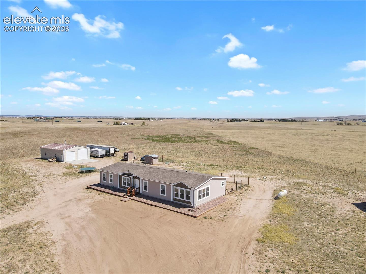Single-level residence featuring a pitched shingle roof, expansive acreage, and a detached two-car garage