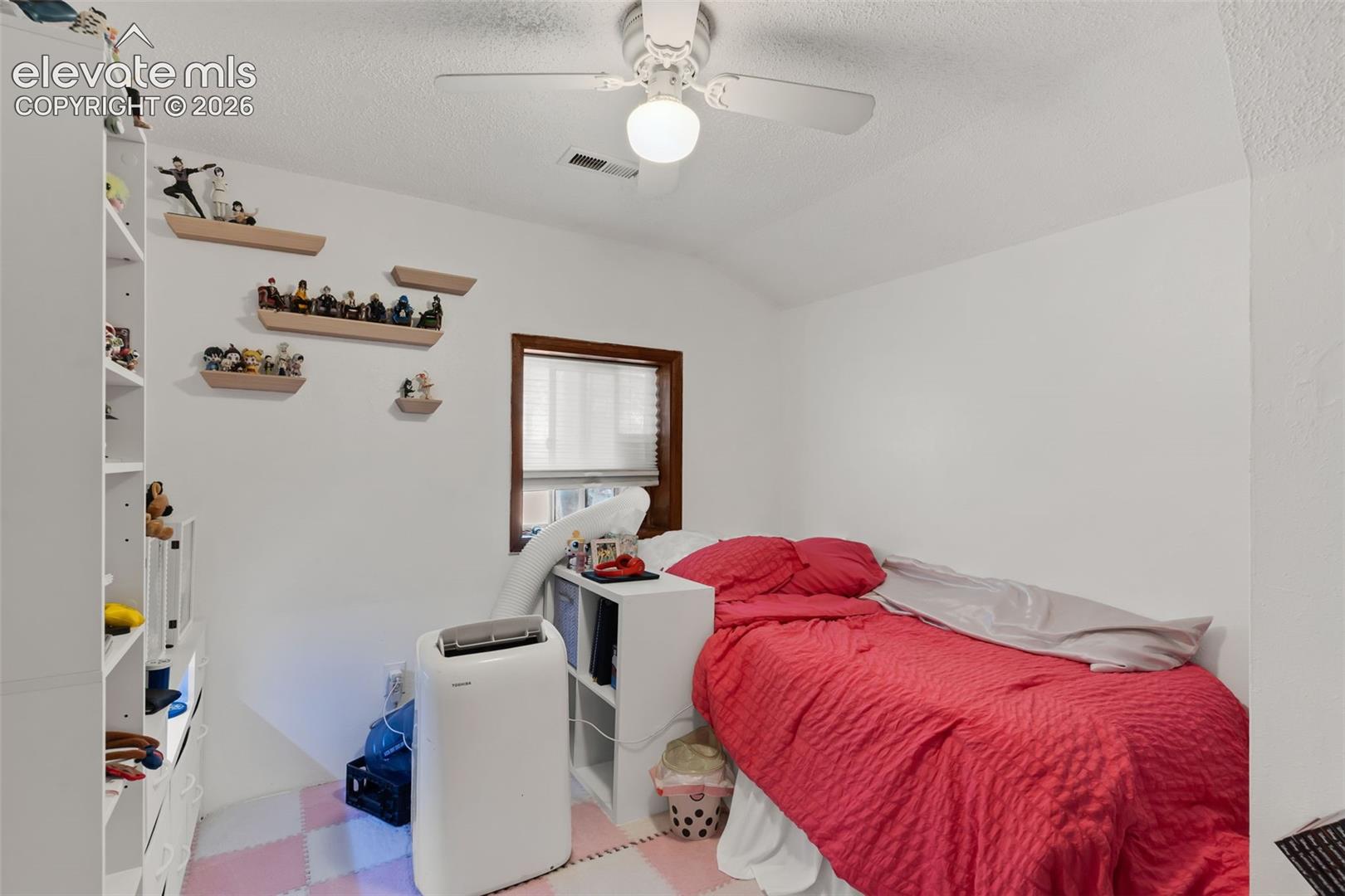 White walls with textured ceiling and a ceiling fan
