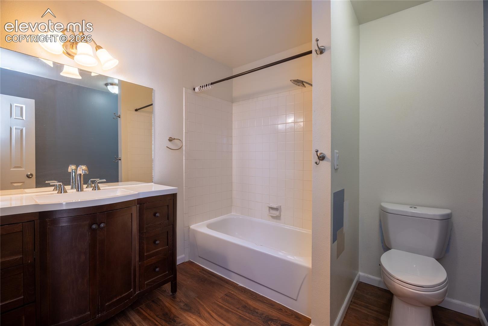 Dark wood-finish vanity with an integrated white sink, chrome fixtures, and a large mirror