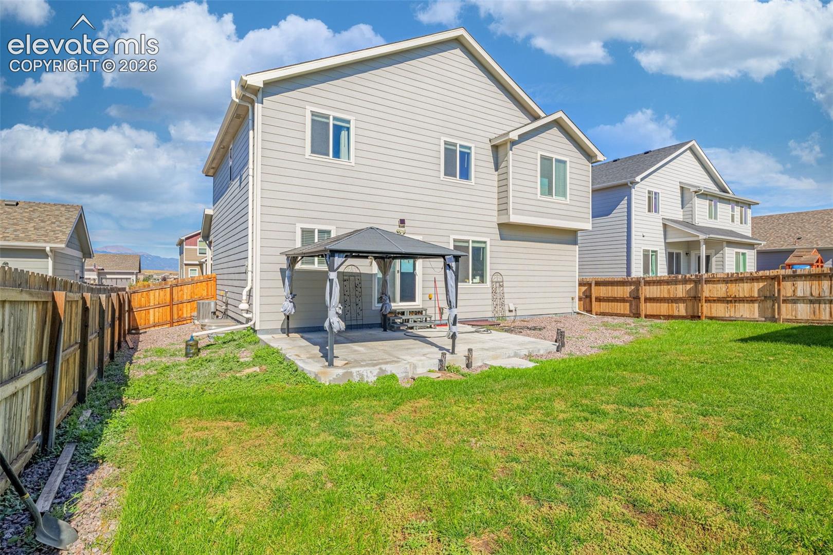 Siding exterior with multiple windows and a concrete patio