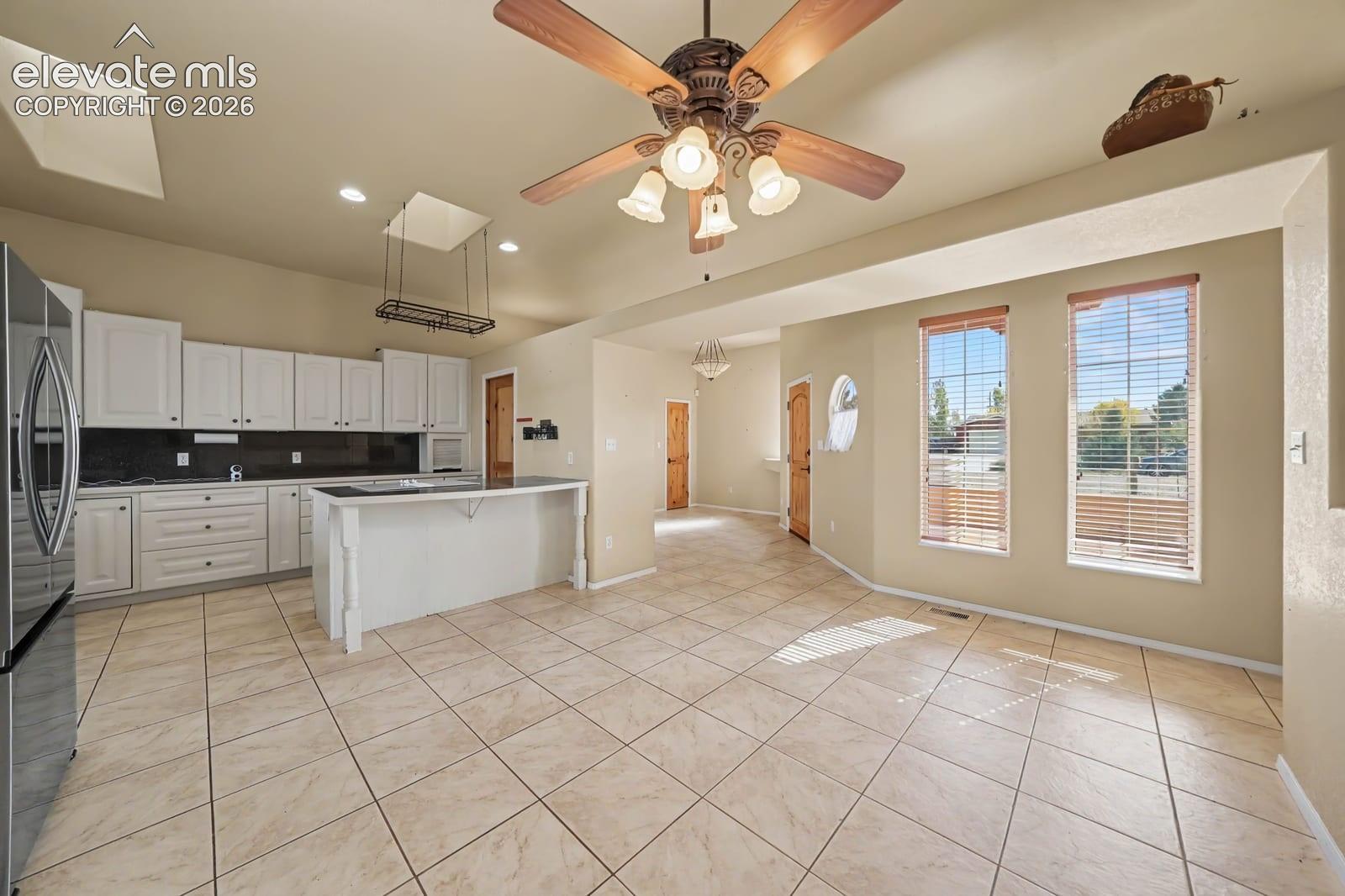 Kitchen featuring white cabinetry, an island, tile flooring, recessed ceiling lighting, and a multi-light ceiling fan