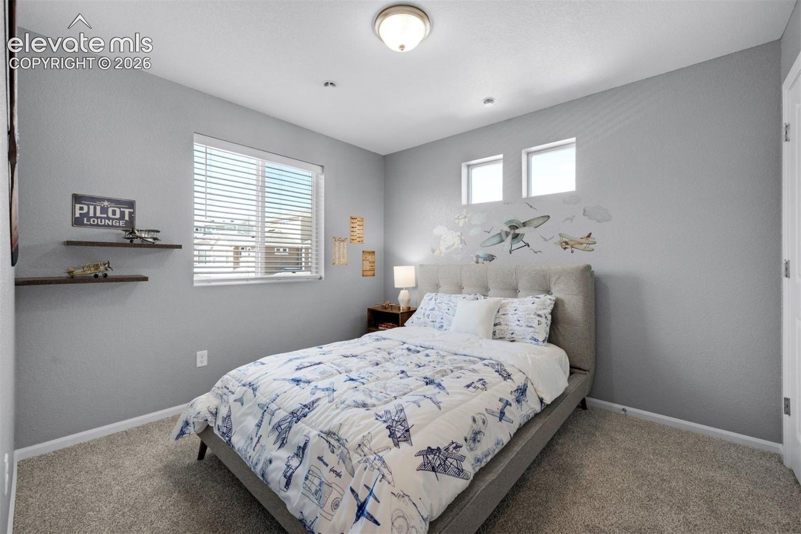 Wall-to-wall carpeting with light gray walls, featuring a large window with blinds and two transom windows
*photos of a model home*