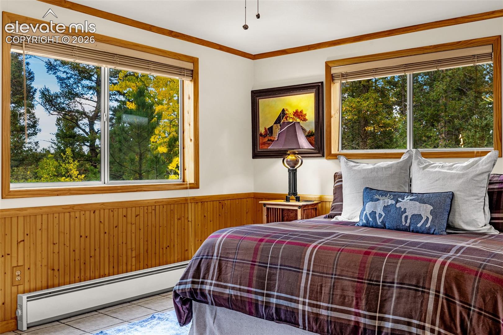 Interior featuring wood wainscoting, dual windows with natural timber trim, and tile flooring