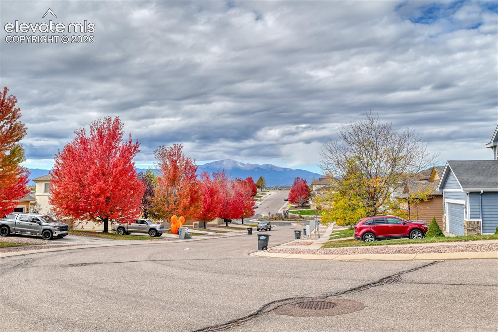 Residential streetscape featuring asphalt paving, concrete sidewalks, and prominent mountain backdrop