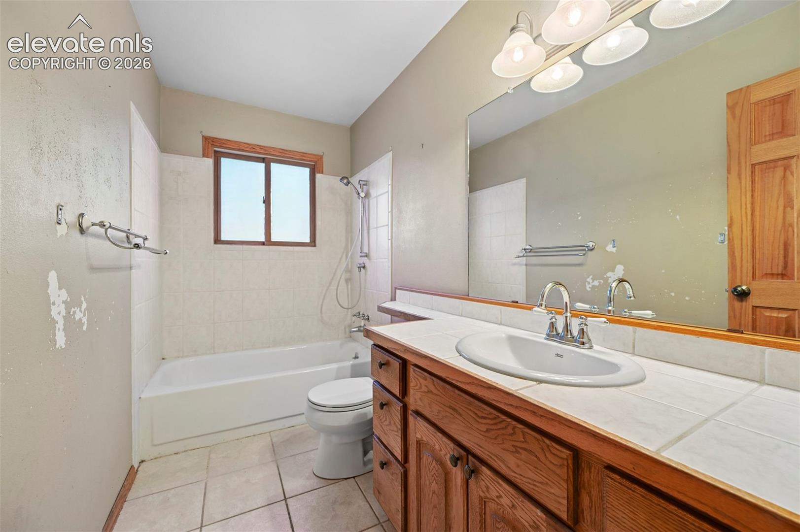 Vanity with wood cabinetry, white tile countertop, and integrated sink