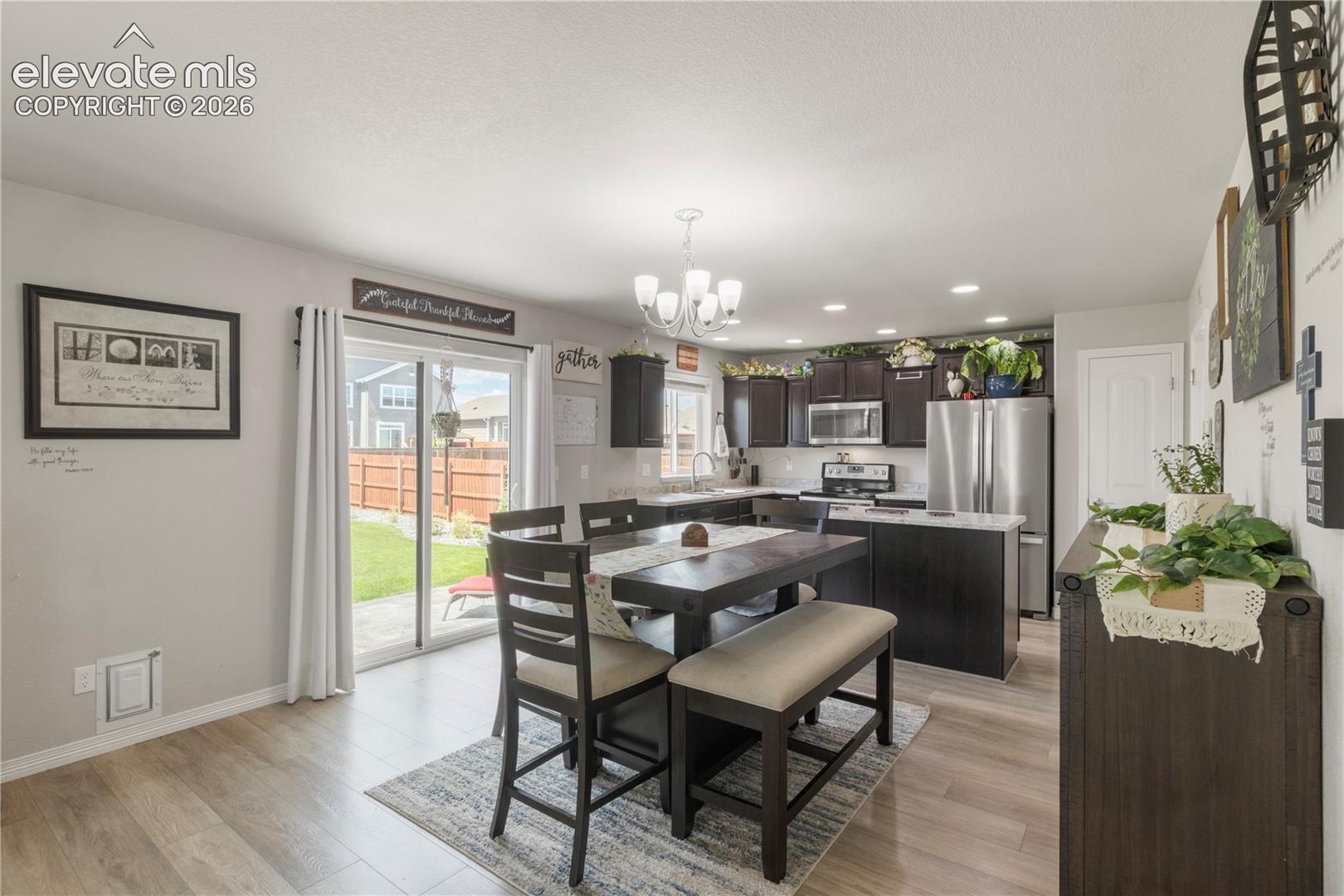 Kitchen featuring wood-finish flooring, dark wood-finish cabinetry, stainless steel appliances, and white countertops