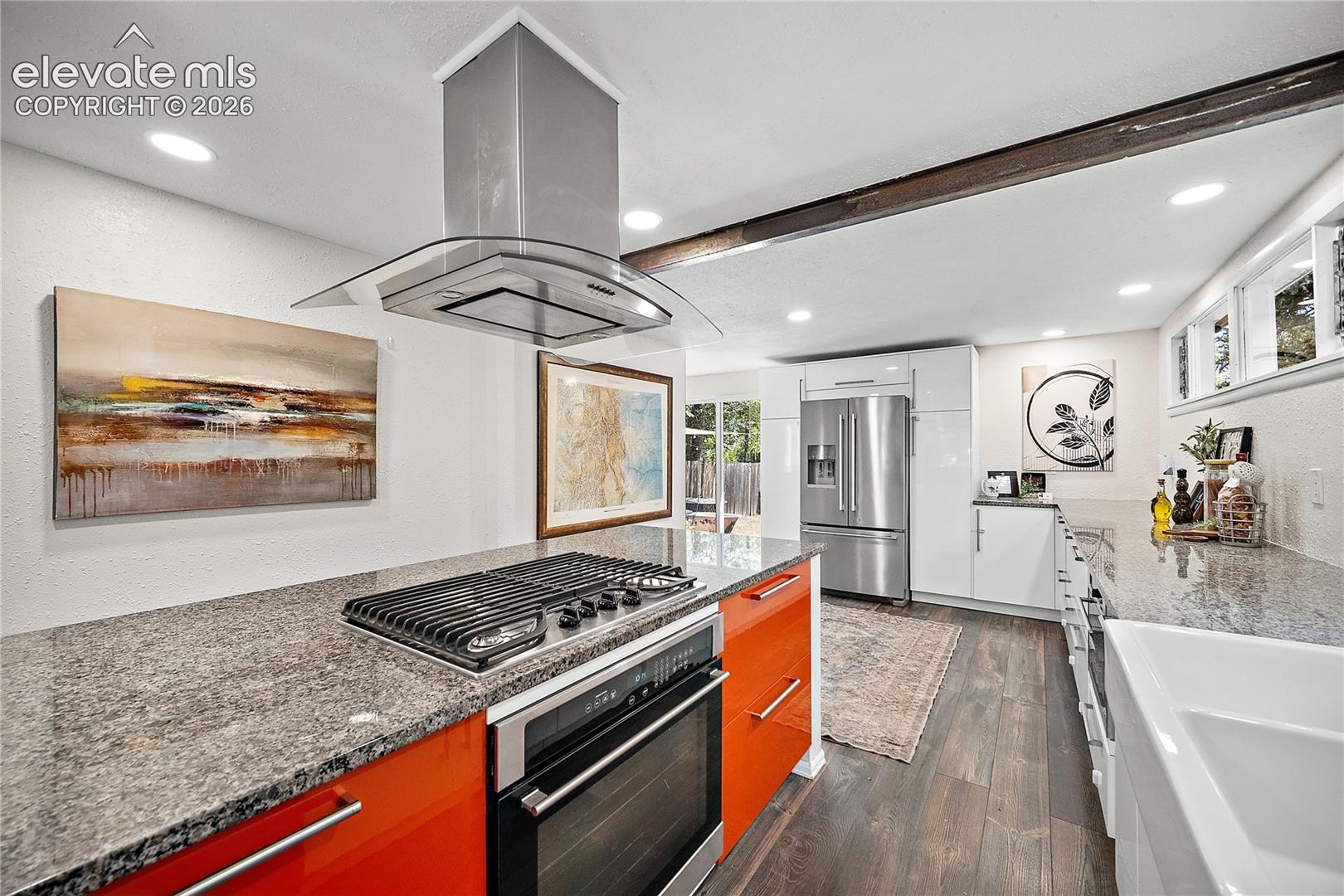Kitchen featuring an island with a built-in gas cooktop, stainless steel range hood, granite countertops, and wood-finish flooring