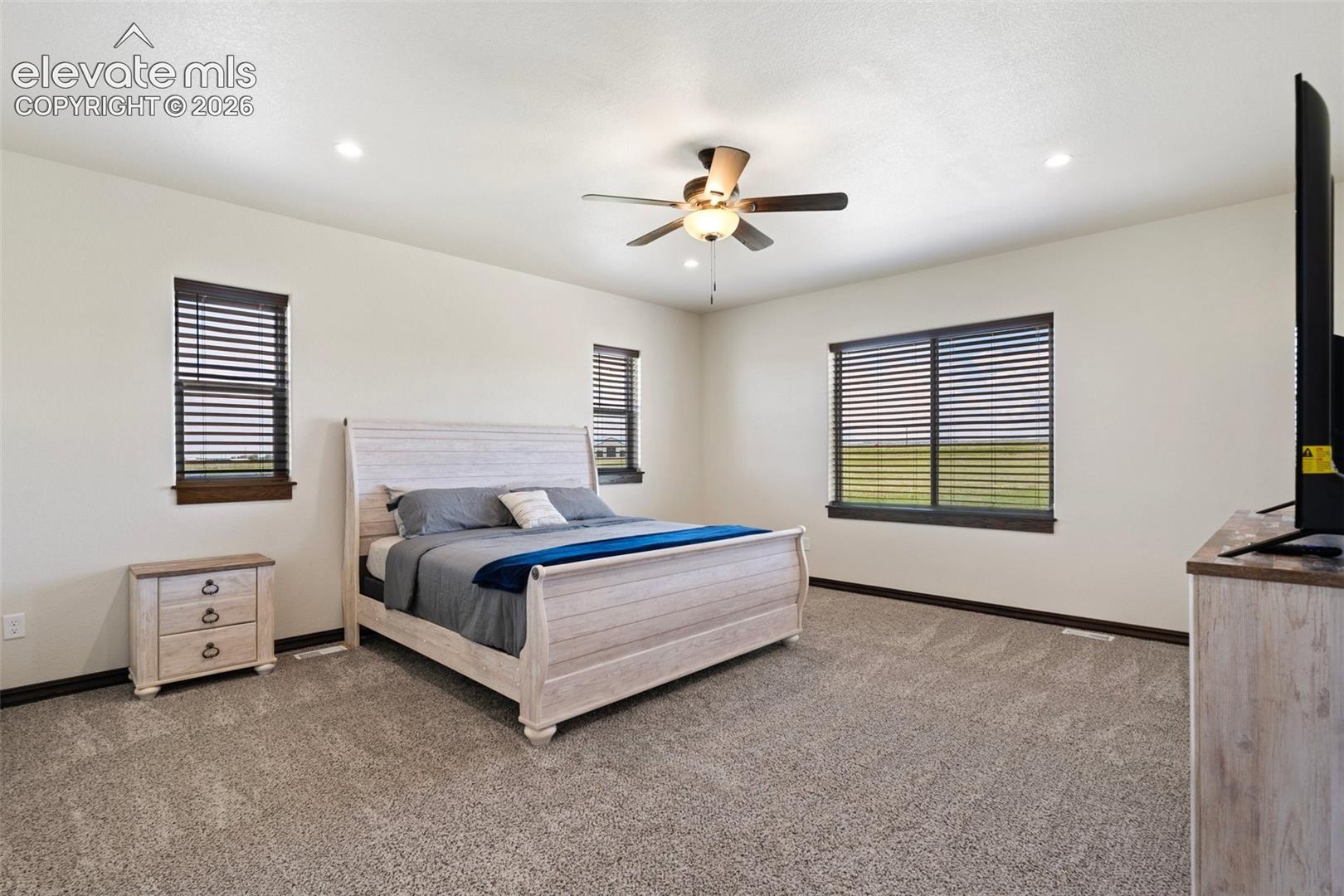 Spacious primary bedroom featuring plush carpeting and a ceiling fan with integrated lighting