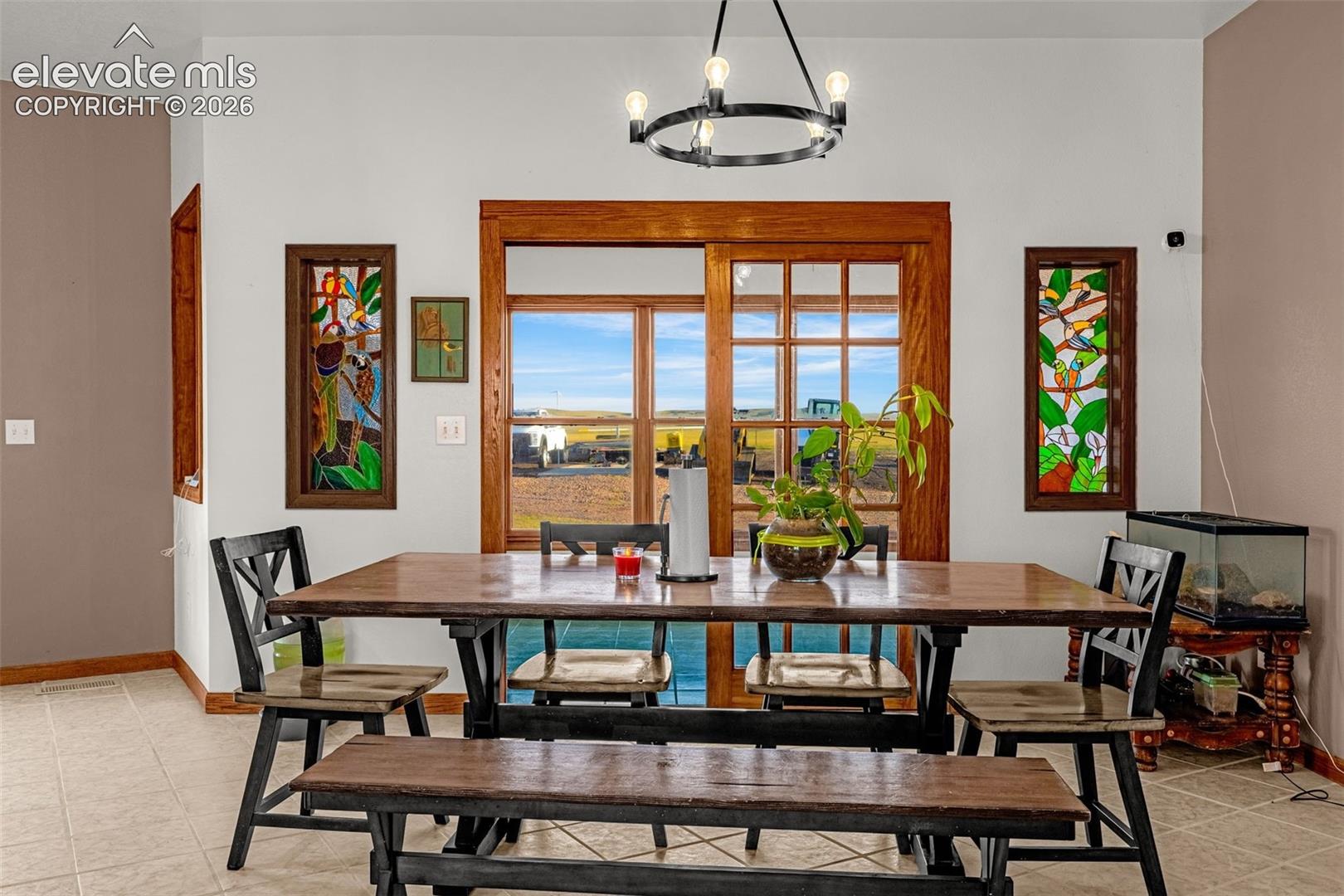 Tiled flooring, wood-framed sliding glass doors, stained glass window features, and a modern circular chandelier