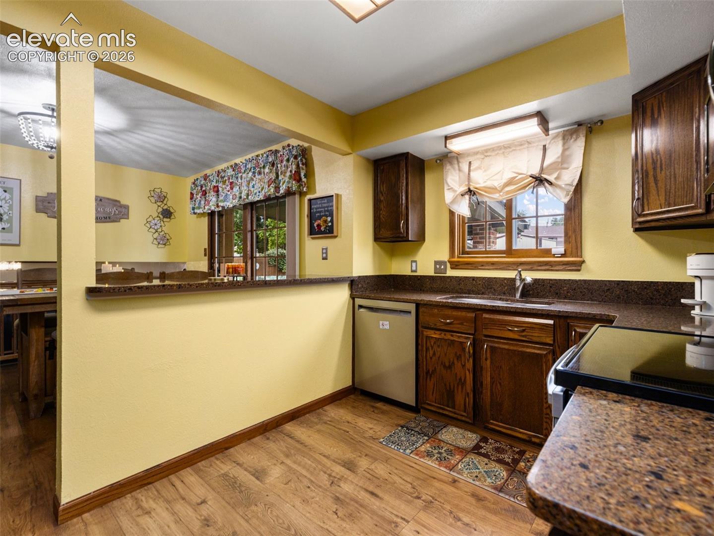 Wood-finish flooring, dark wood cabinetry, and a built-in dishwasher
