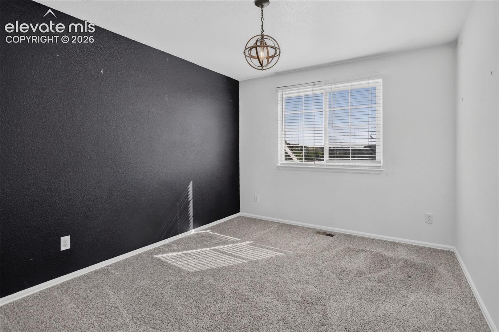 Carpet flooring, single window with blinds, ceiling-mounted light fixture, and contrasting wall color