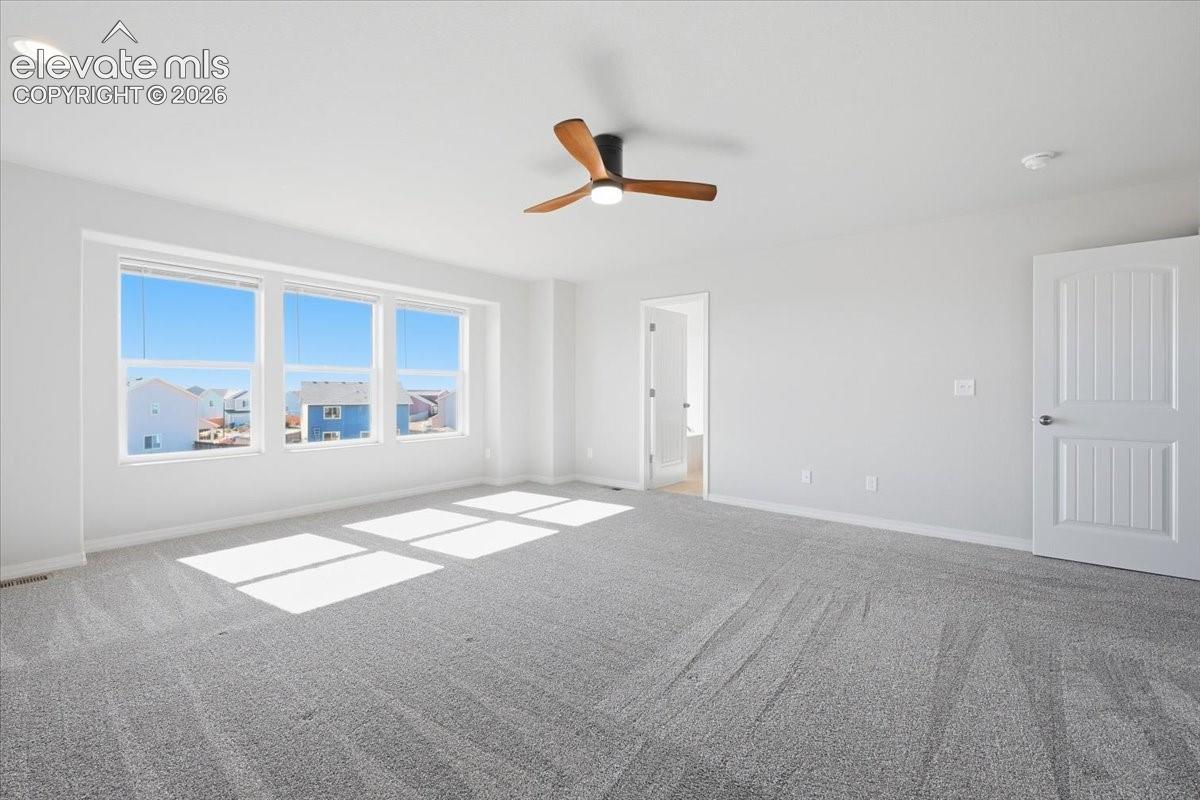 Interior space featuring grey wall-to-wall carpeting, three-pane window assembly, recessed lighting, and a contemporary ceiling fan with wood-finish blades
