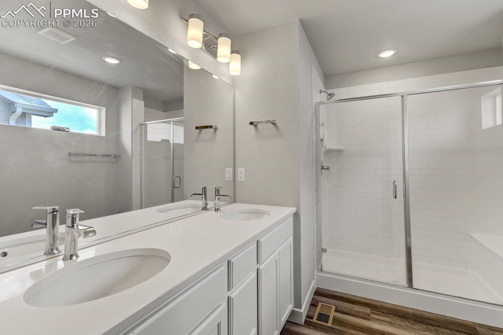Master Bathroom with double vanity, dark wood-type flooring, a shower stall, and recessed lighting