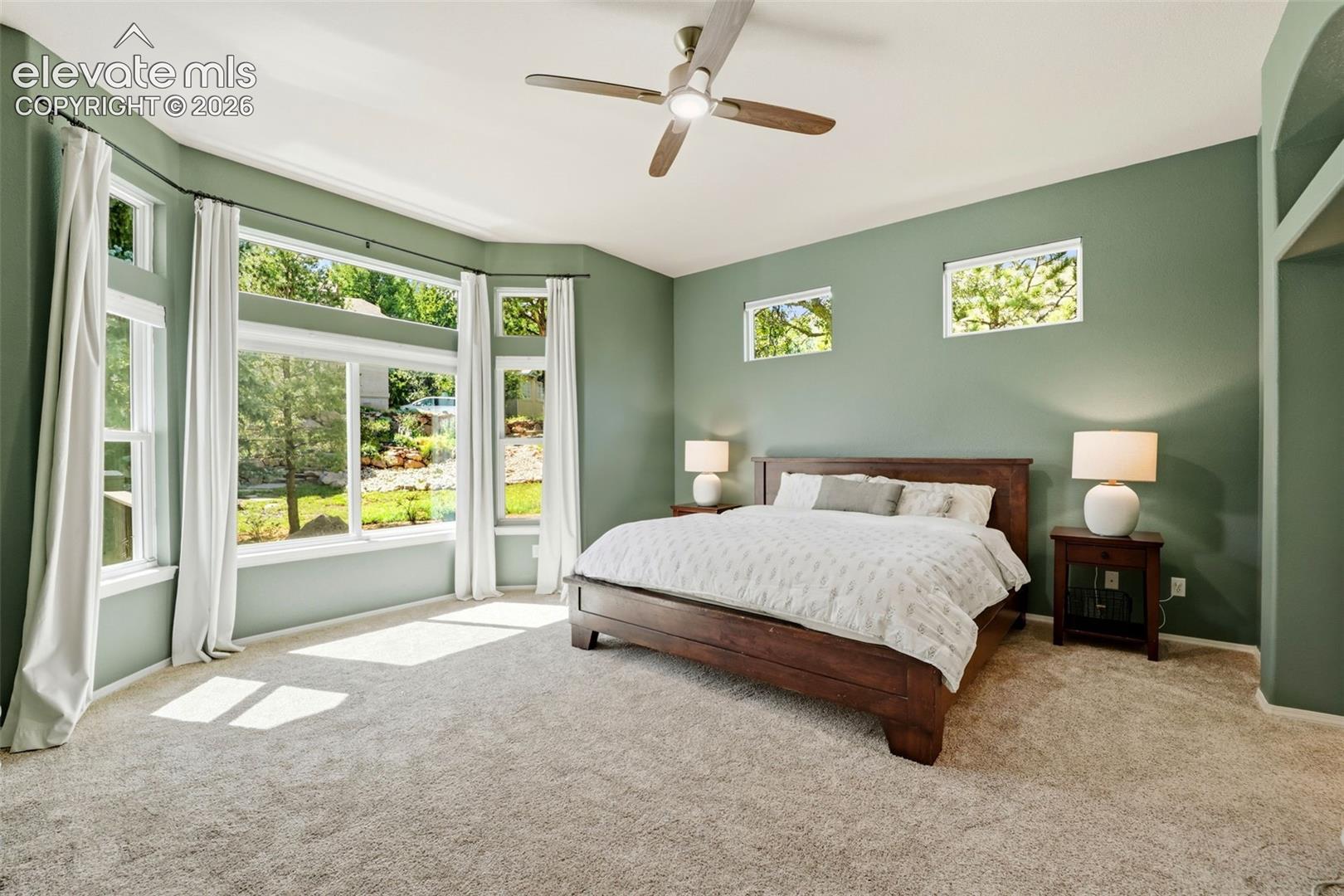 Expansive bay windows with upper transom windows overlooking the backyard
