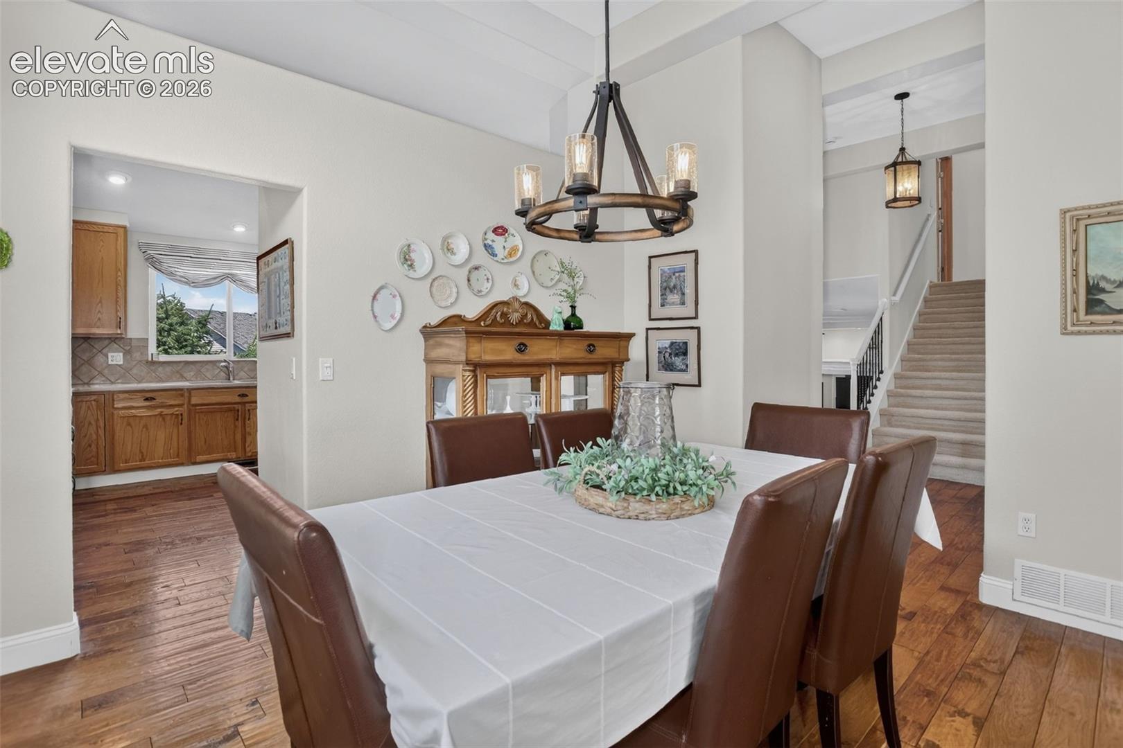 Dining area featuring wood-finish flooring, a contemporary chandelier, and an arched entry to the kitchen
