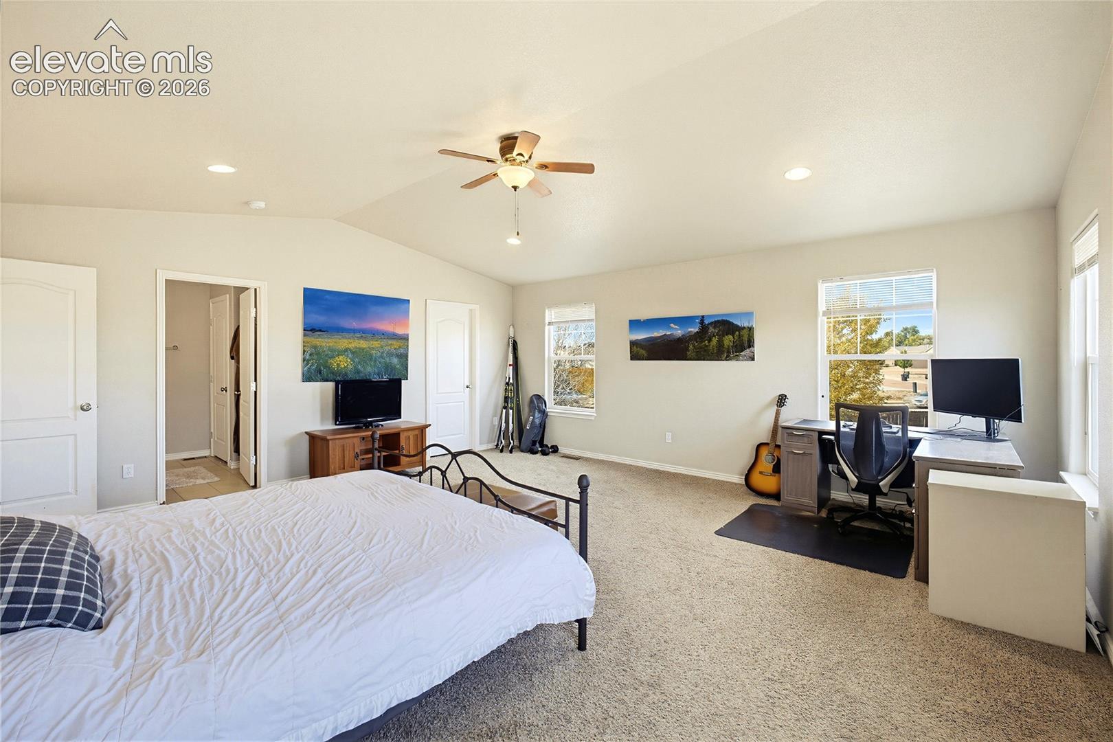 Vaulted ceilings, carpeted flooring, recessed lighting, ceiling fan, and multiple windows