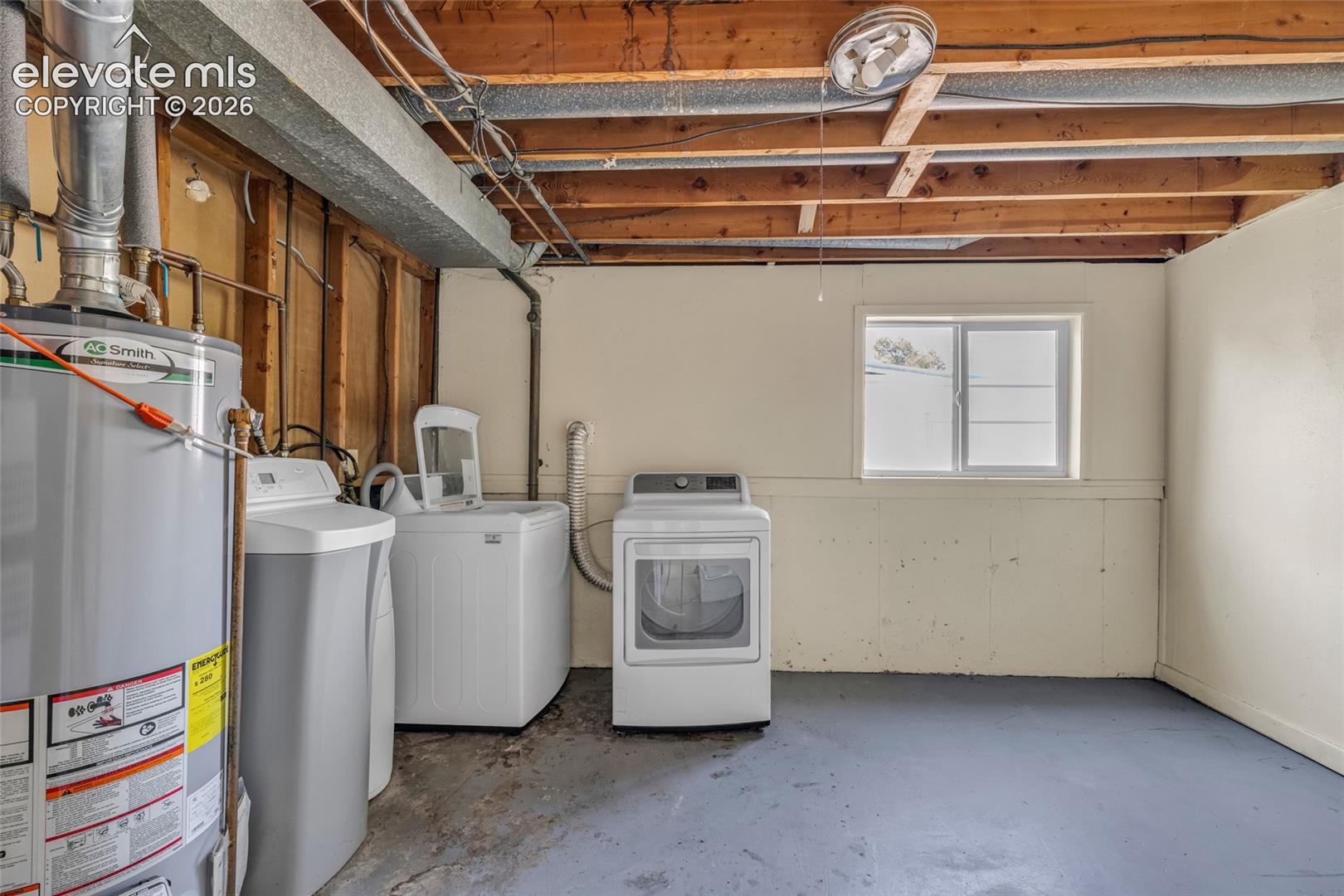 Utility space featuring a water heater, washer, dryer, water softener, and a window