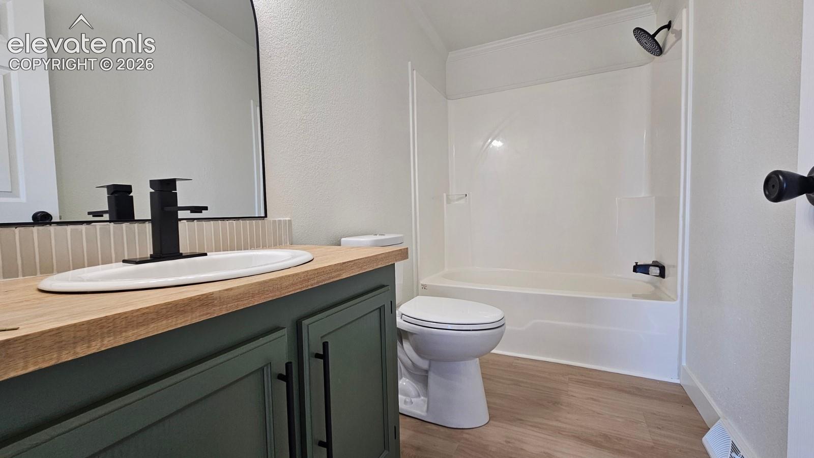 Bathroom featuring a wood-tone vanity, arched mirror, matte black fixtures, and wood-finish flooring