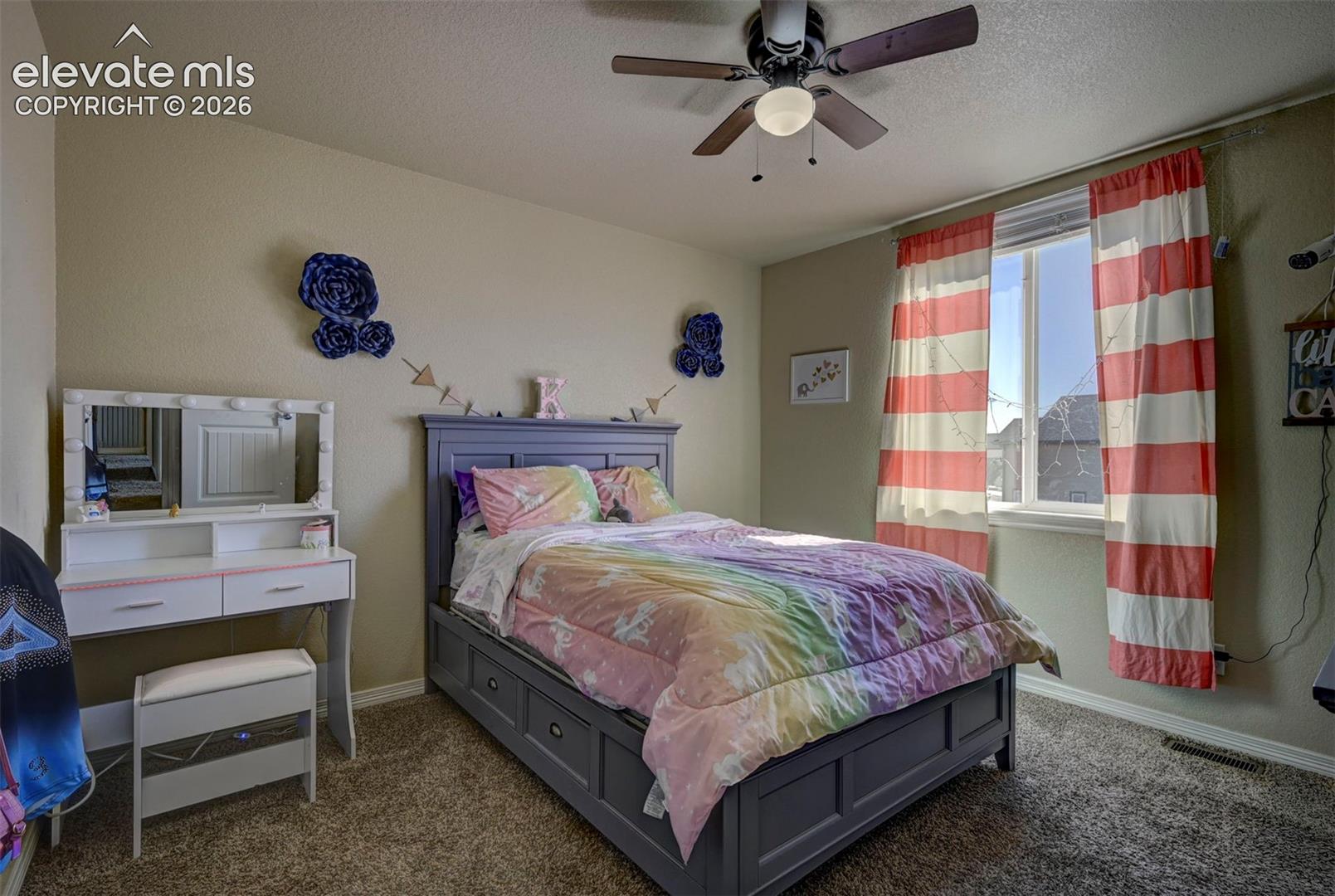 Carpeted bedroom featuring a ceiling fan, a window with a white frame, and a built-in bed frame with storage drawers