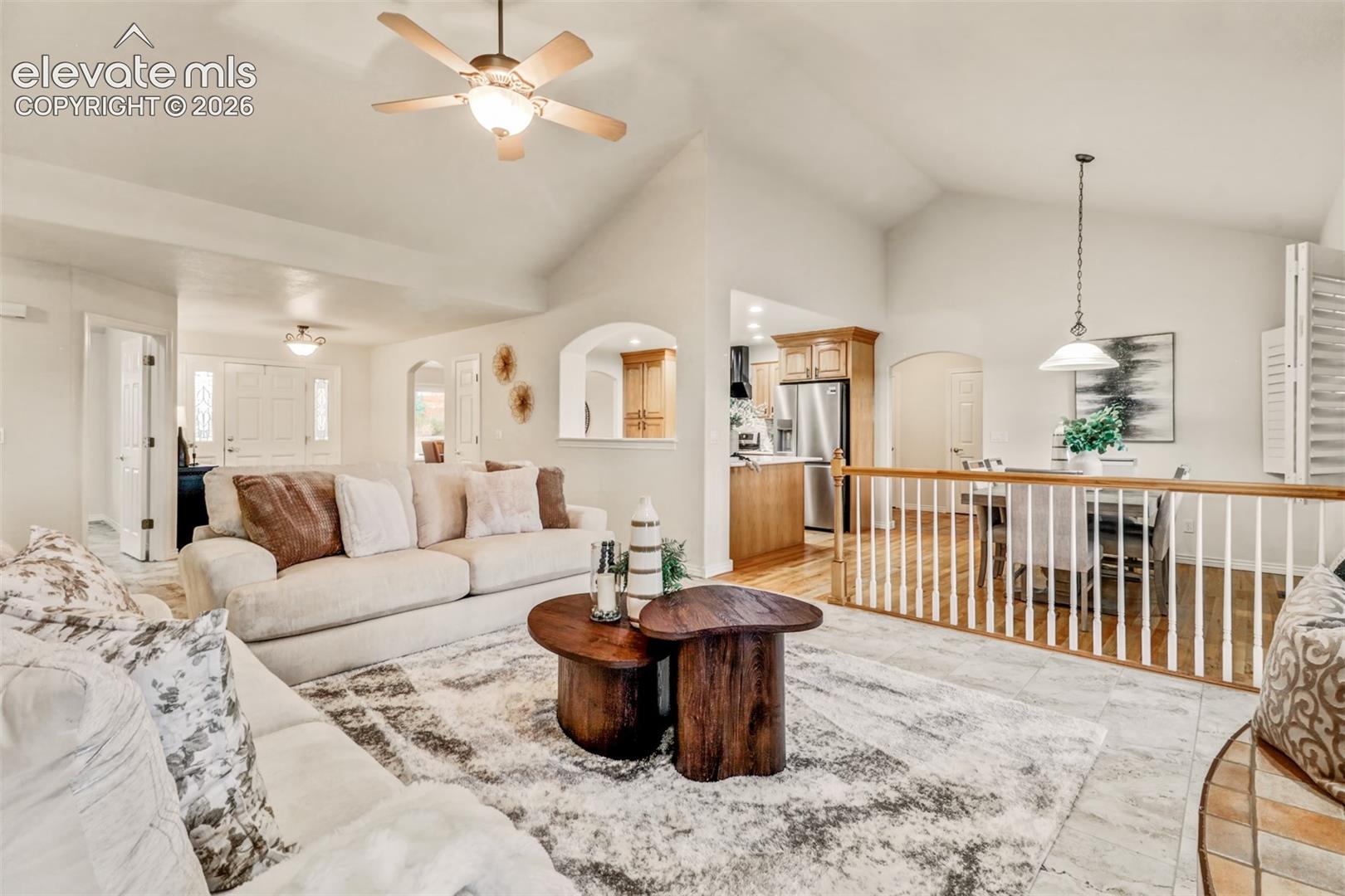Vaulted ceilings, tile flooring, built-in wooden cabinetry, arched architectural details, and a wood-spindle stair railing
