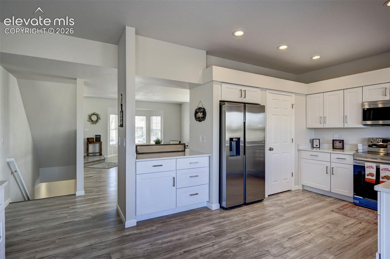 Kitchen featuring white shaker-style cabinetry, wood-finish flooring, recessed lighting, and stainless steel appliances