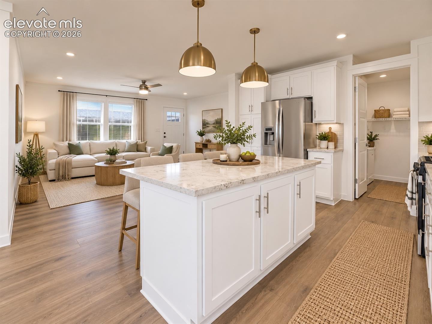 Kitchen & Living Area – Expansive kitchen island anchors the open-concept main level, with abundant cabinetry, stainless steel appliances, pendant lighting, and clear sightlines into the living area.