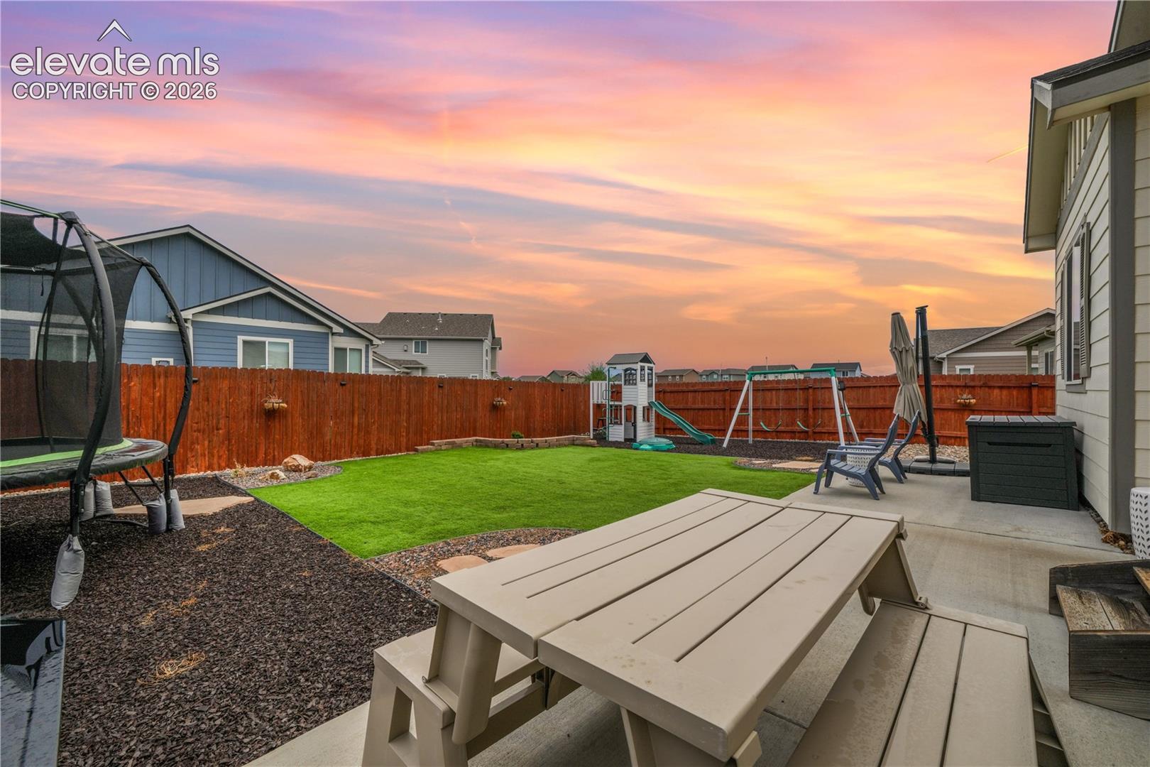 Private backyard featuring a concrete patio, wood fence, and artificial turf lawn