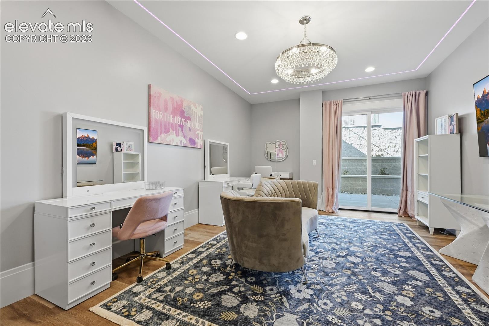 Tray ceiling with recessed lighting, crystal chandelier, wood-finish flooring, and glass sliding door