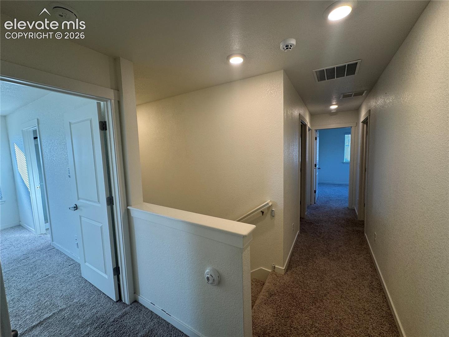 Interior hallway featuring recessed ceiling lighting, textured wall finishes, and wall-to-wall carpeting