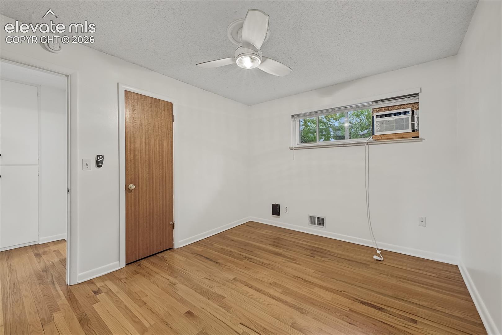 Room featuring wood-finish flooring, a ceiling fan with light fixture, and a single-hung window