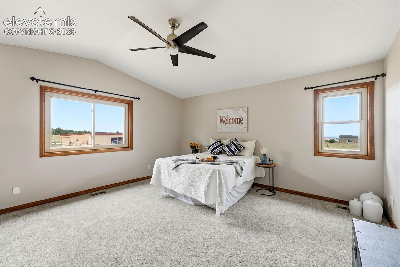 Vaulted ceiling with a ceiling fan, light-colored carpeting, and light-toned wall paint
