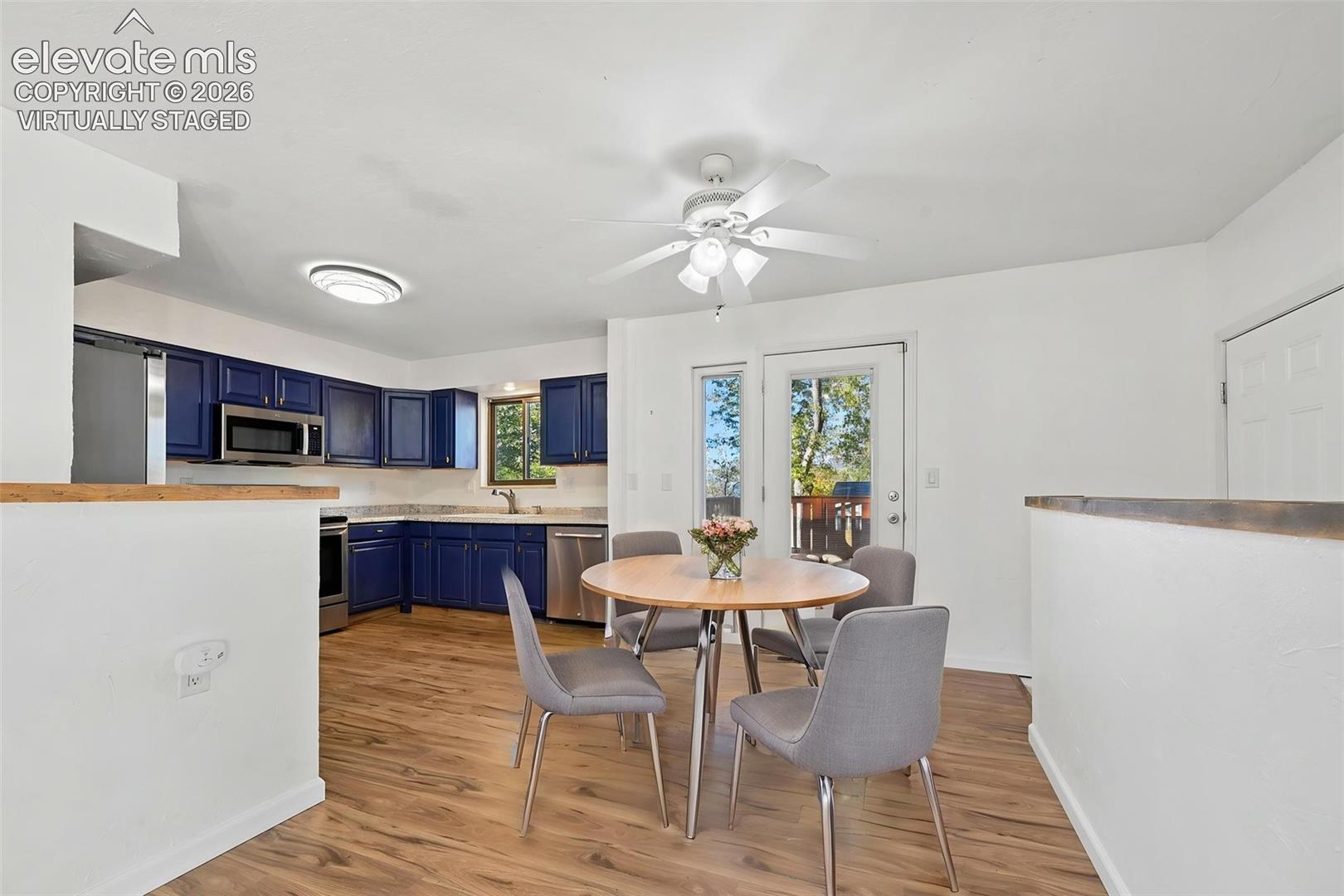 Virtually staged Kitchen/dining area featuring blue cabinetry, formica countertops, new LVP flooring, and a ceiling fan with integrated lighting